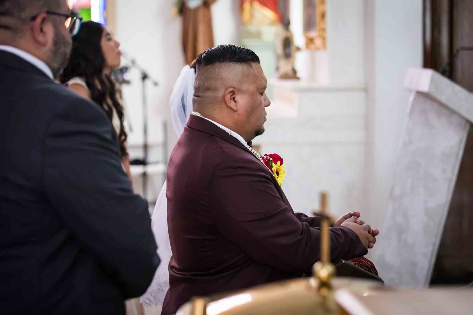 St. Henry Catholic Church wedding photos of bride and groom kneeling with eyes closed during lasso ceremony