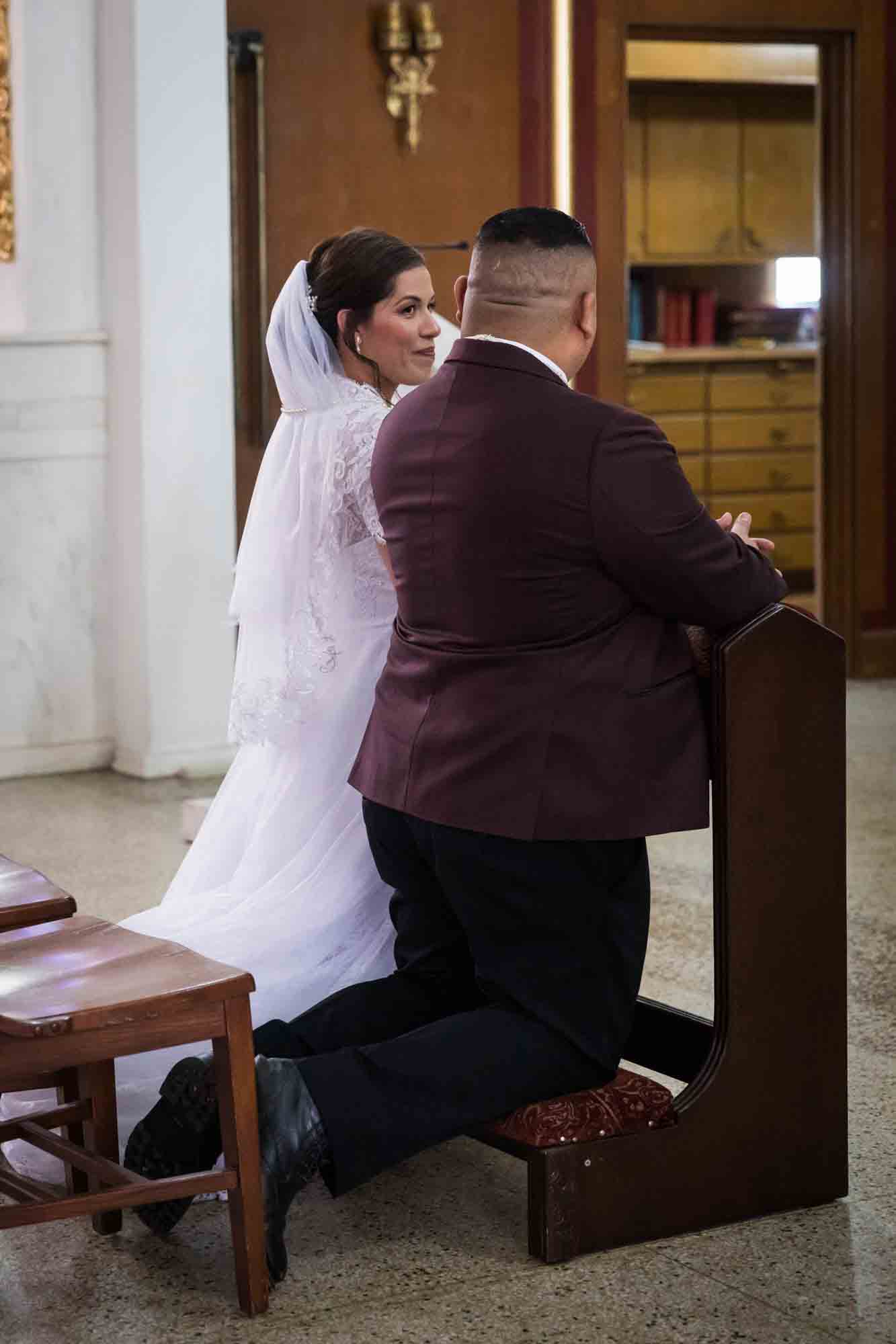 St. Henry Catholic Church wedding photos of bride looking at groom while kneeling at altar