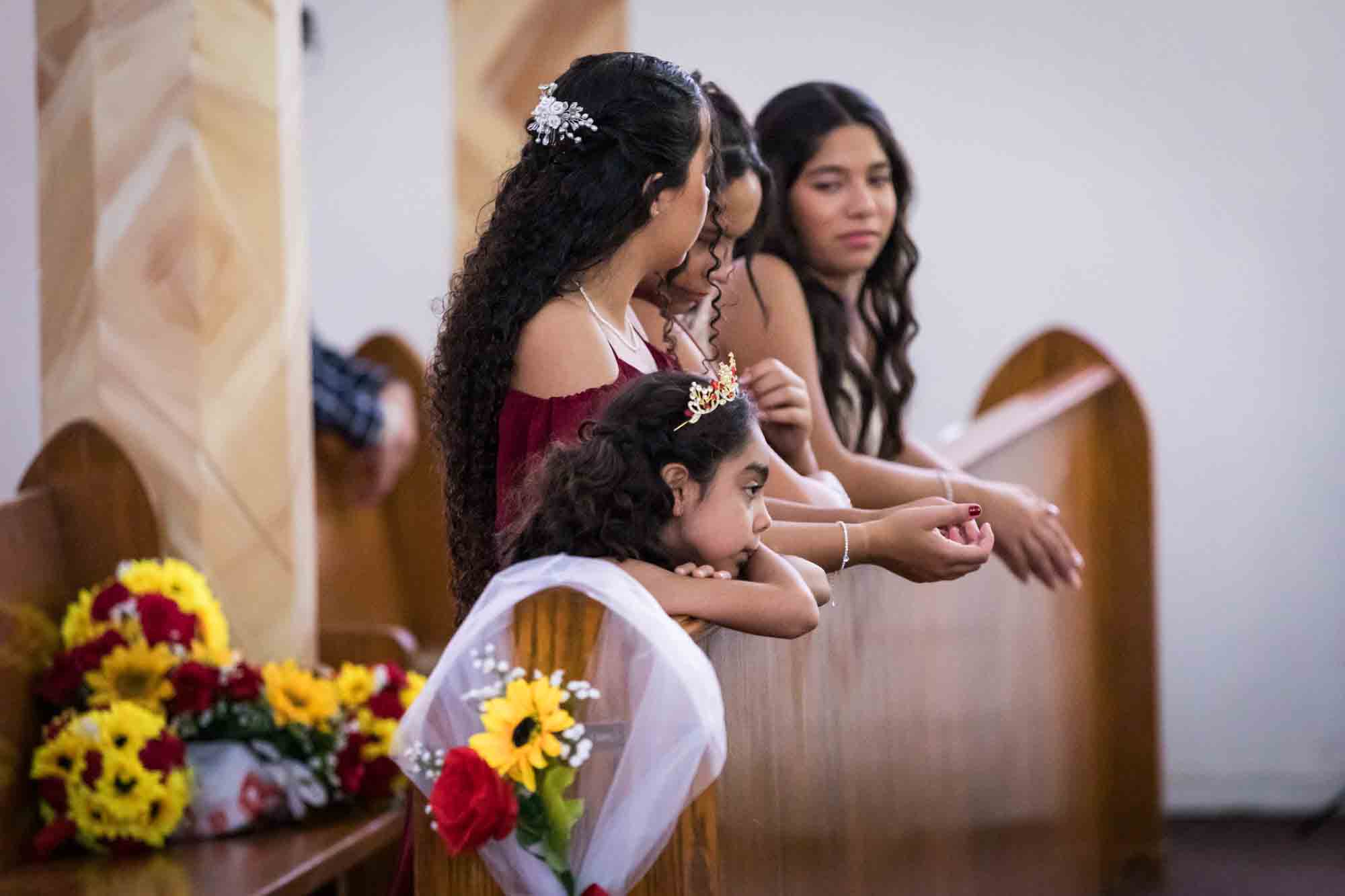 St. Henry Catholic Church wedding photos of bridesmaids and flower girl leaning on pew