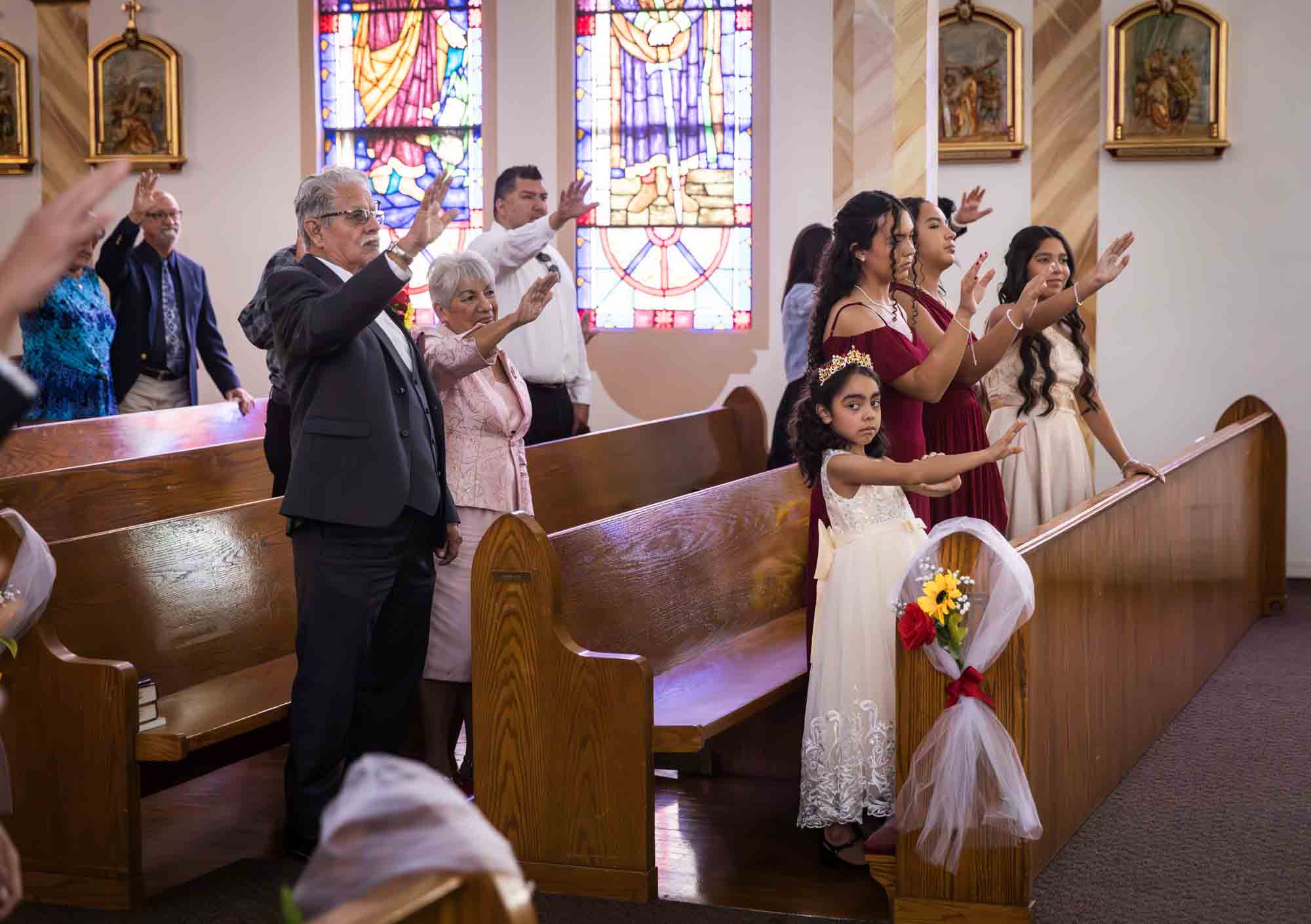 St. Henry Catholic Church wedding photos of guests holding hands in the air while standing in pews