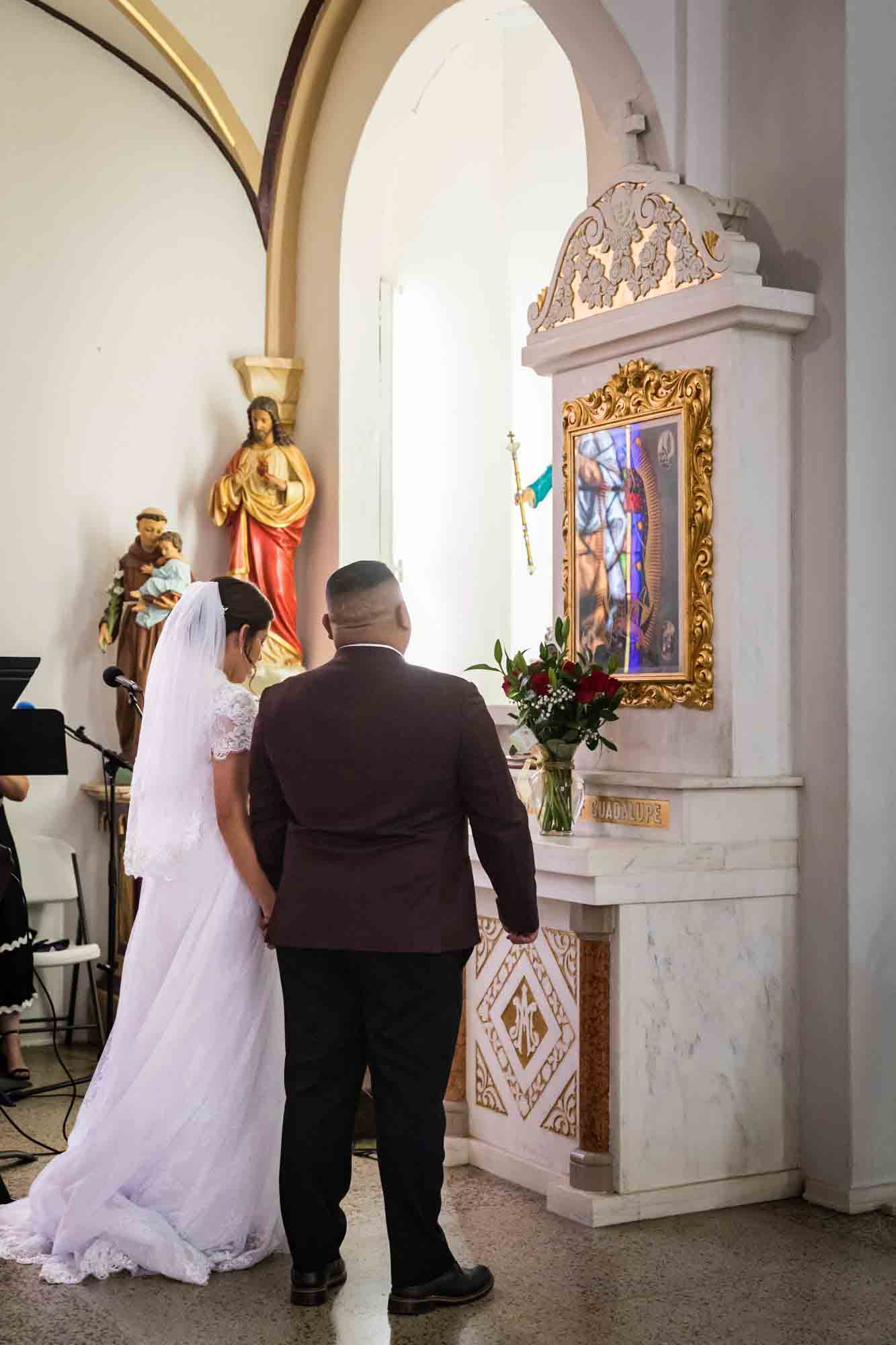 St. Henry Catholic Church wedding photos of bride and groom standing in front of the Our Lady of Guadalupe altar