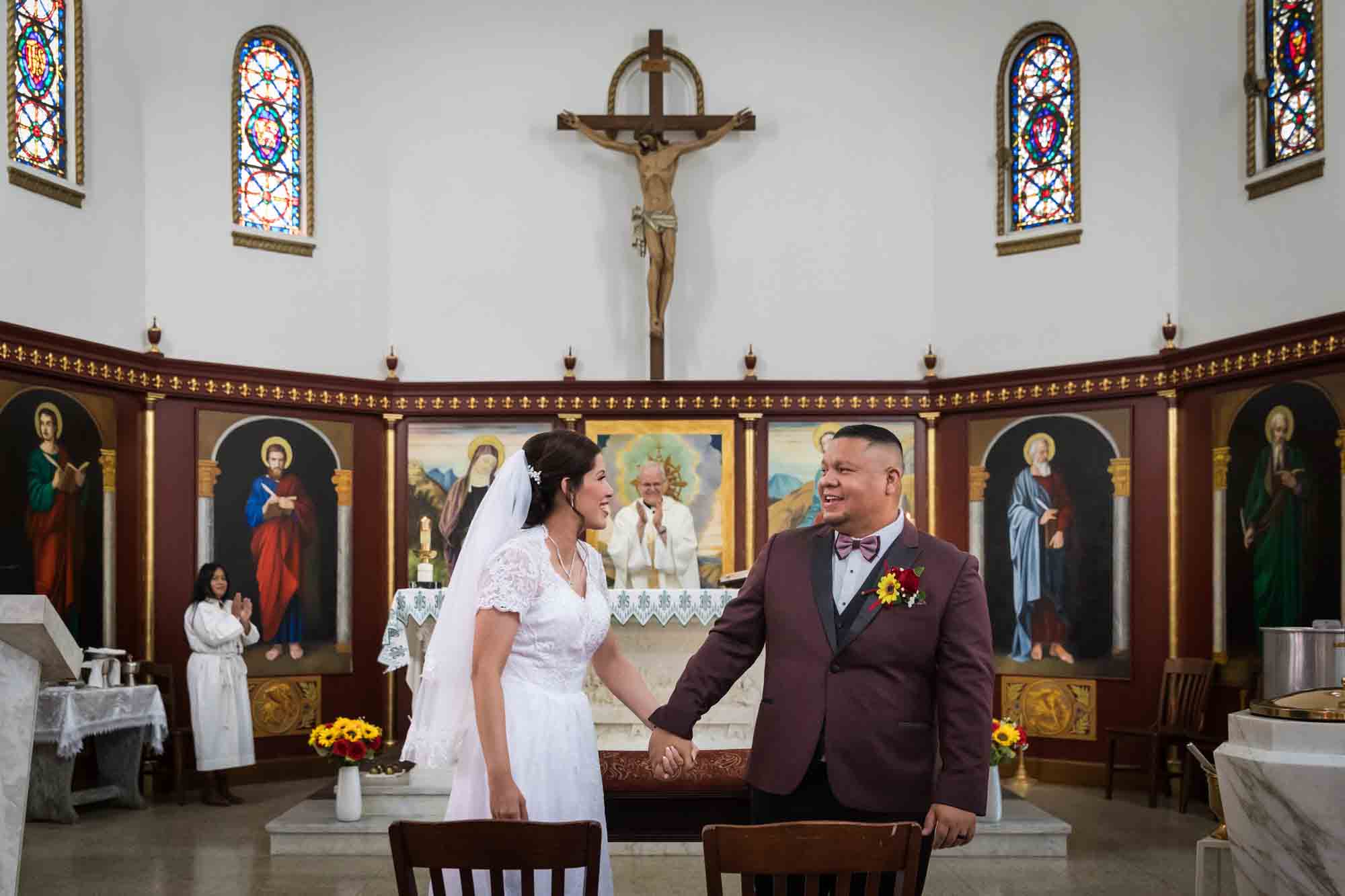 St. Henry Catholic Church wedding photos of bride and groom holding hands at altar of church