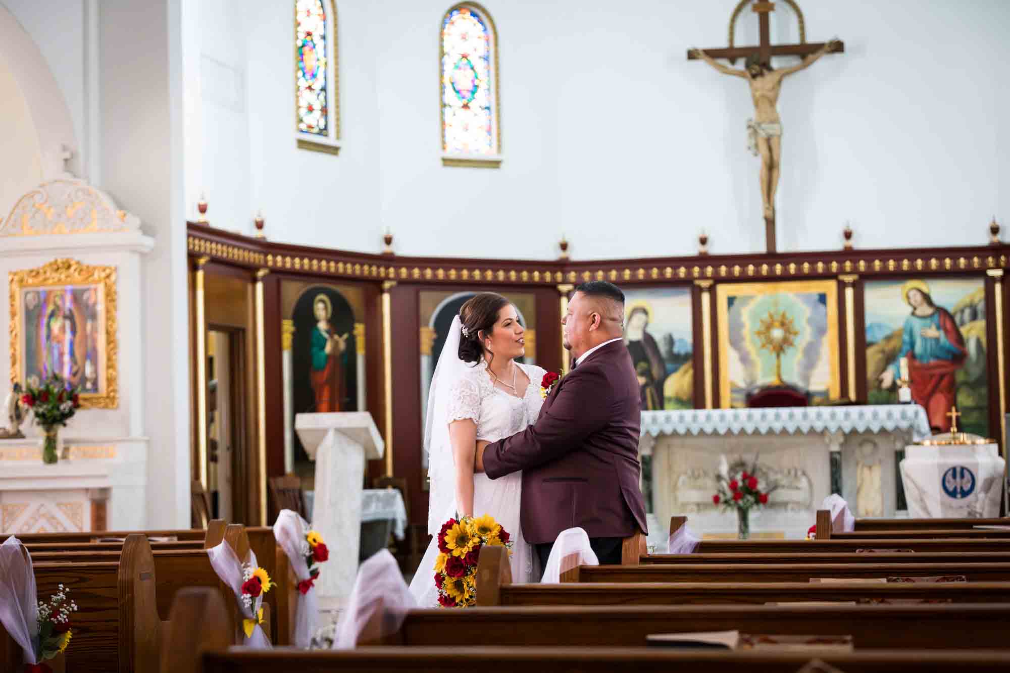 St. Henry Catholic Church wedding photos of bride and groom hugging in aisle of church