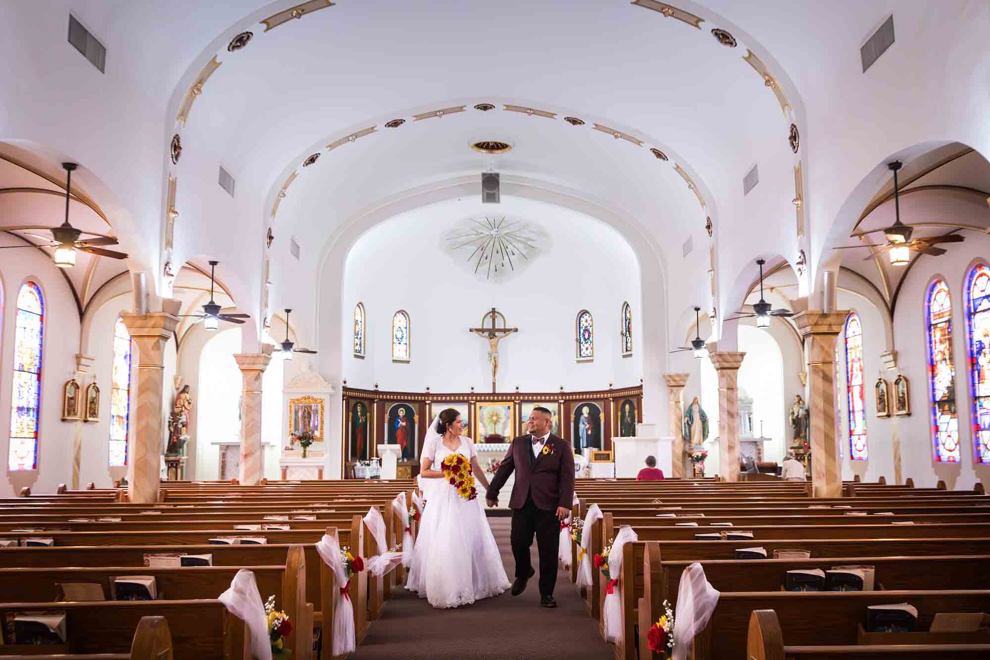 St. Henry Catholic Church wedding photos of bride and groom holding hands and walking down aisle of church