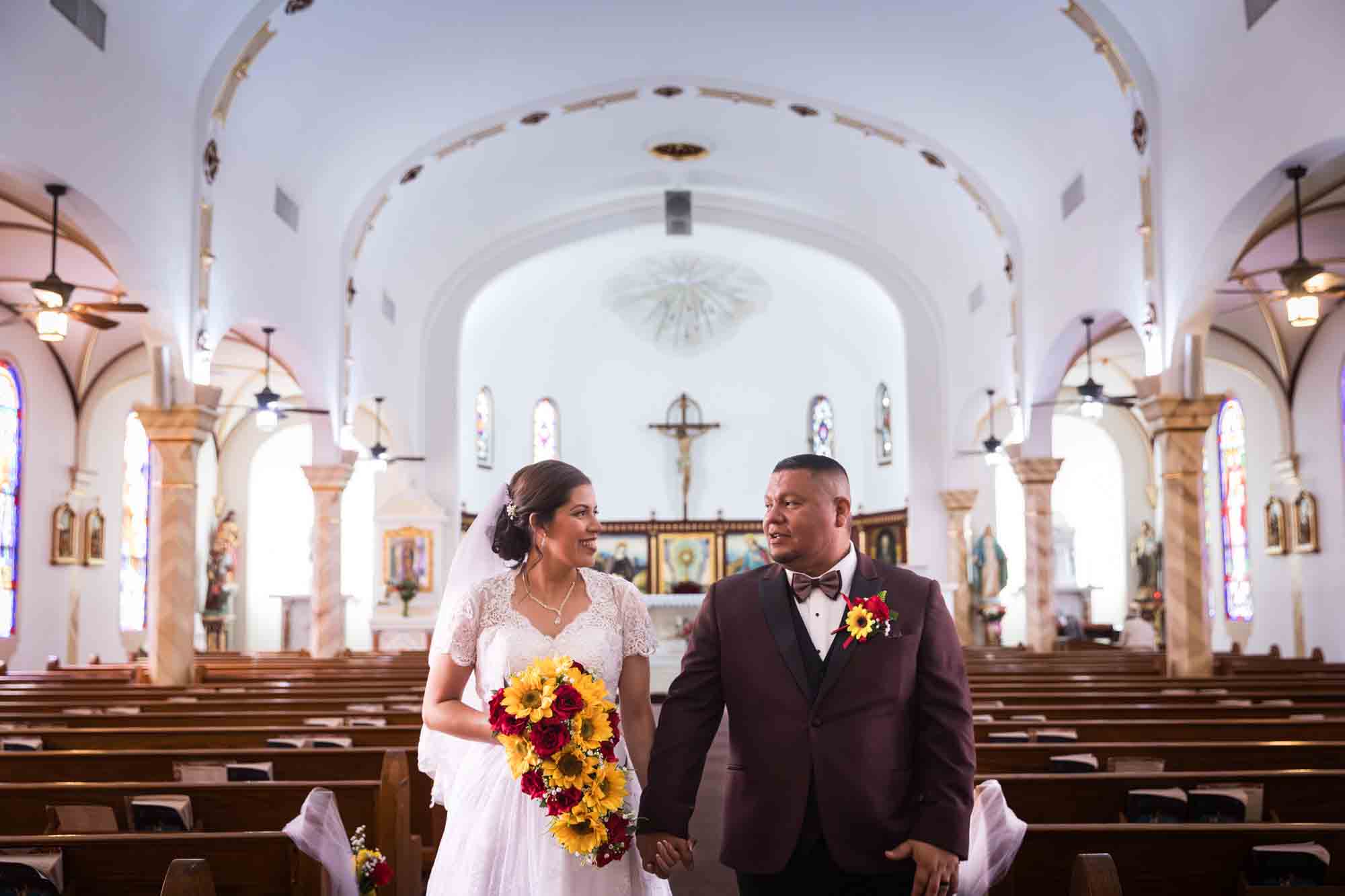 St. Henry Catholic Church wedding photos of bride and groom holding hands and walking down aisle of church