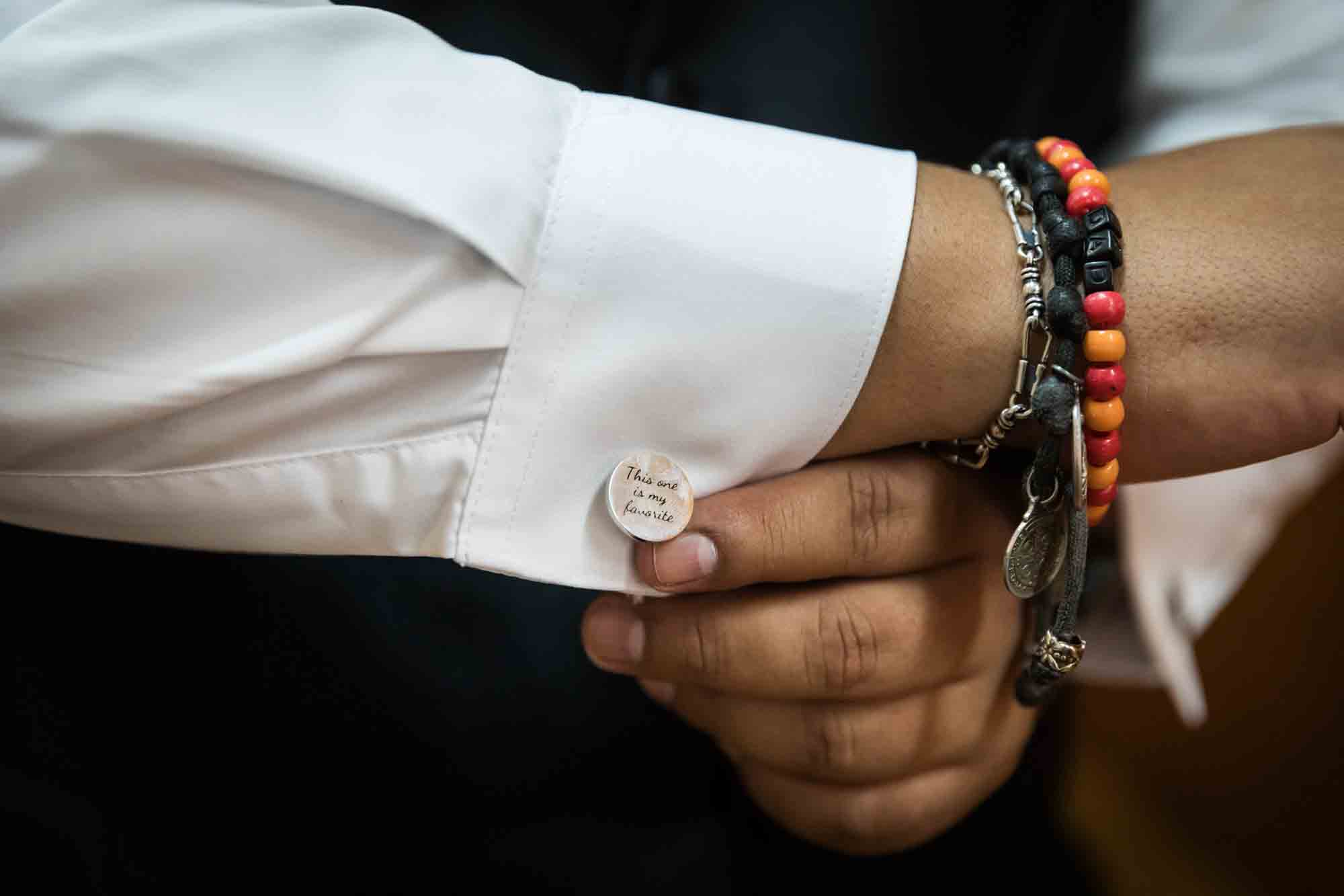 Close up of man showing engraved cufflink and bracelets