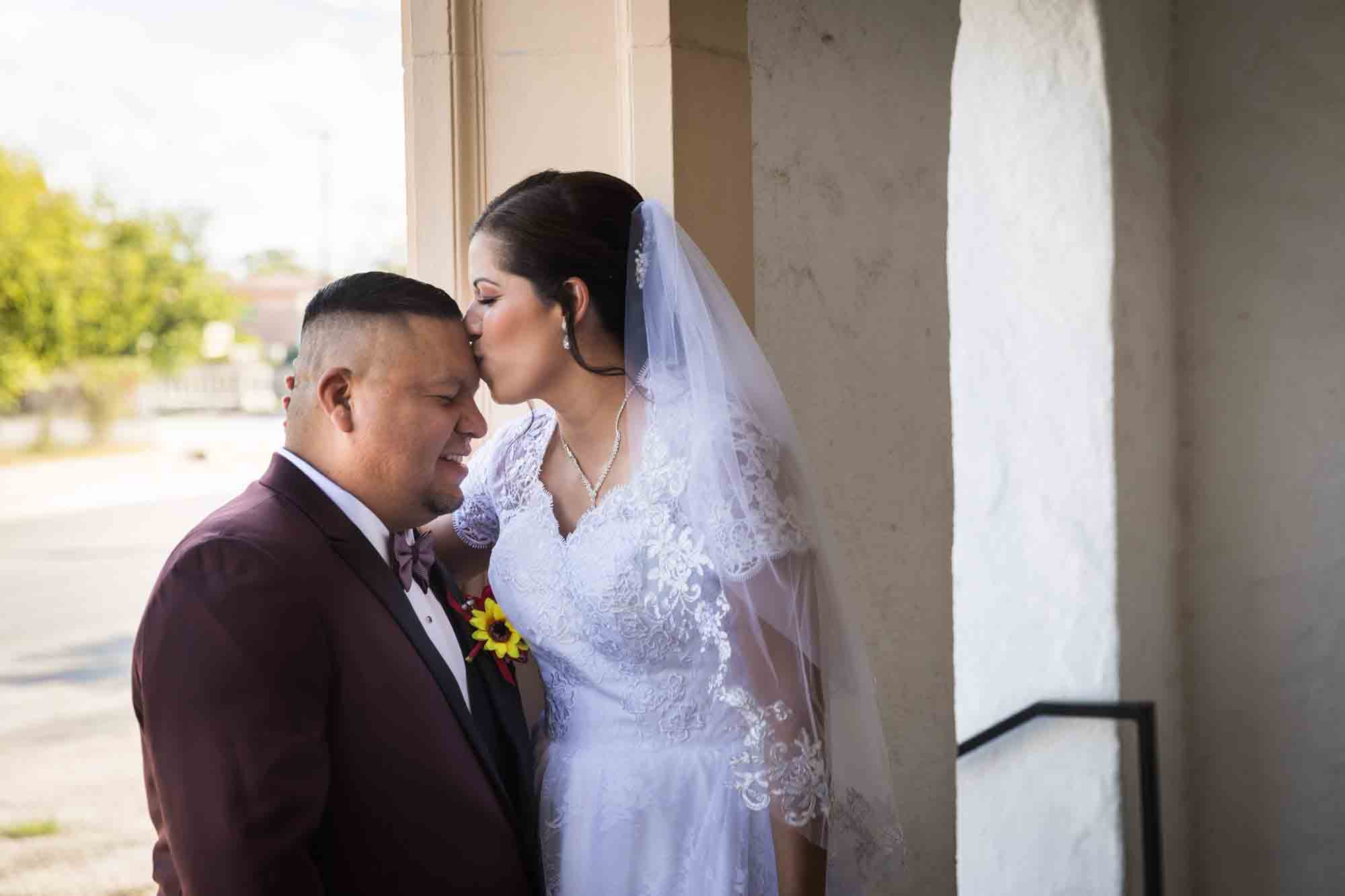 St. Henry Catholic Church wedding photos of bride kissing groom on forehead in entrance to church