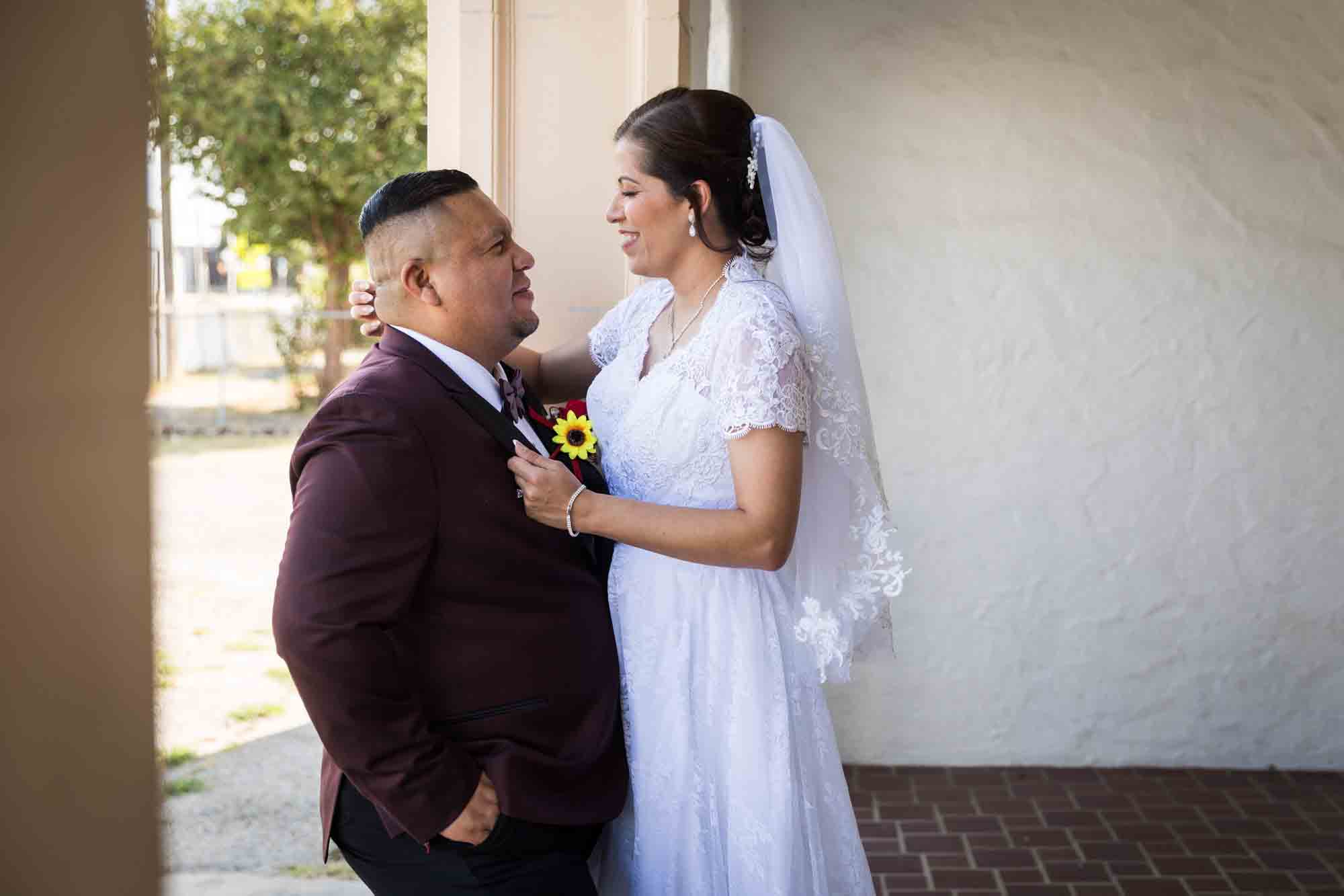 St. Henry Catholic Church wedding photos of bride and groom hugging in front of white wall