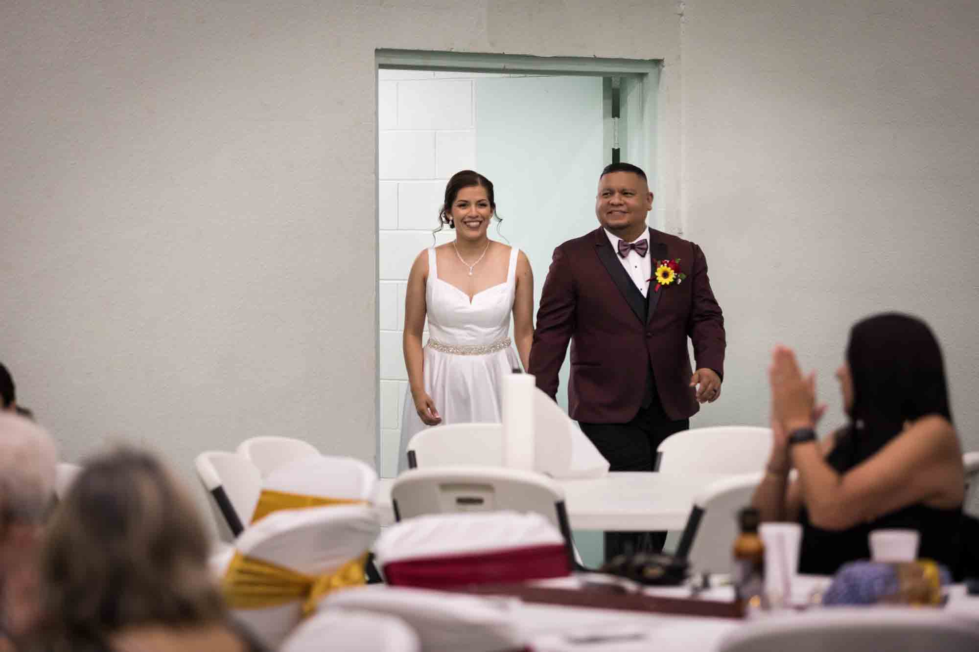 St. Henry Catholic Church wedding photos of bride and groom entering reception in front of tables and guests