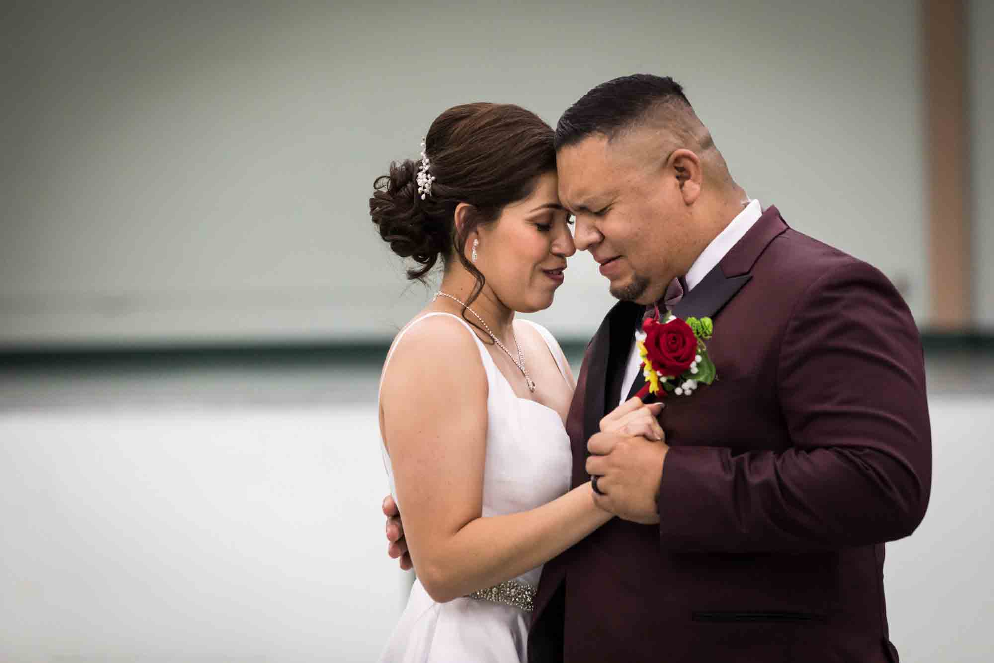 Bride and groom dancing close and and touching foreheads with eyes closed during a St. Henry Catholic Church wedding reception