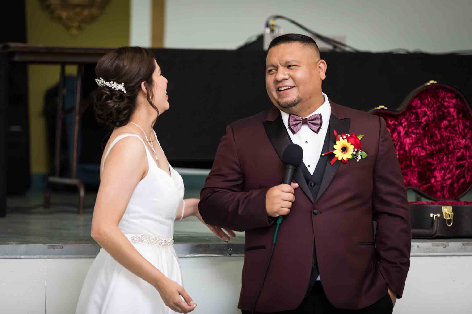 Bride laughing and groom holding microphone during a St. Henry Catholic Church wedding reception