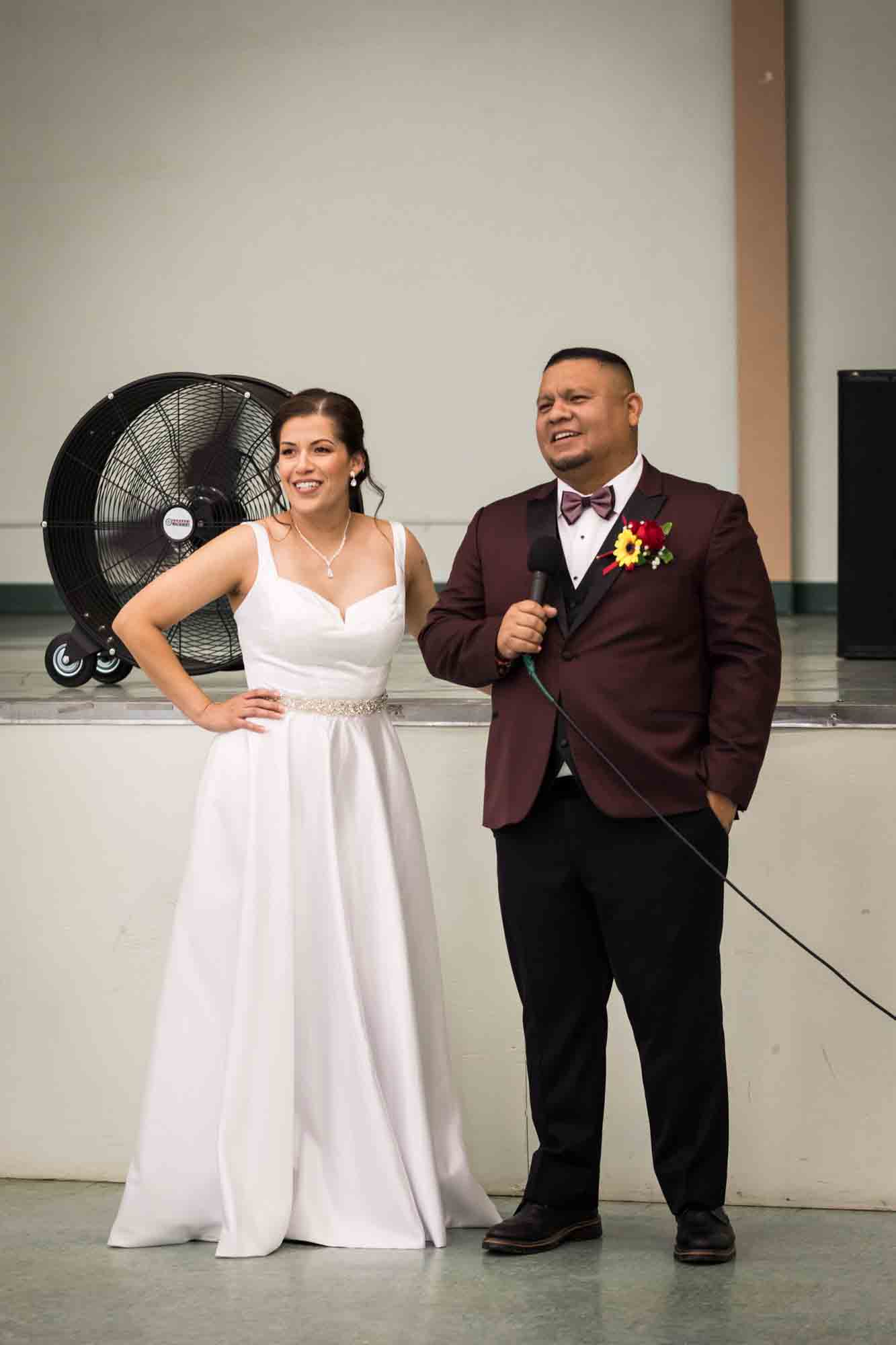 Bride and groom making a speech and holding microphone during a St. Henry Catholic Church wedding reception