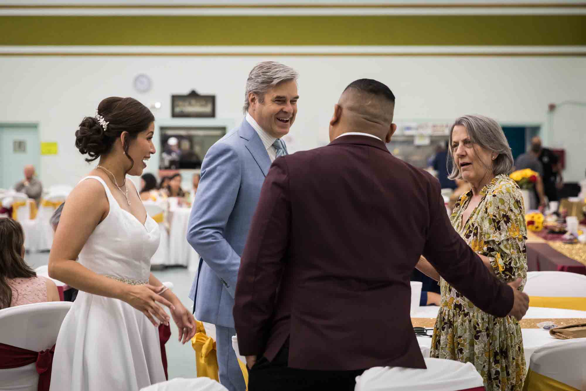 Bride and groom talking to older couple during a St. Henry Catholic Church wedding reception