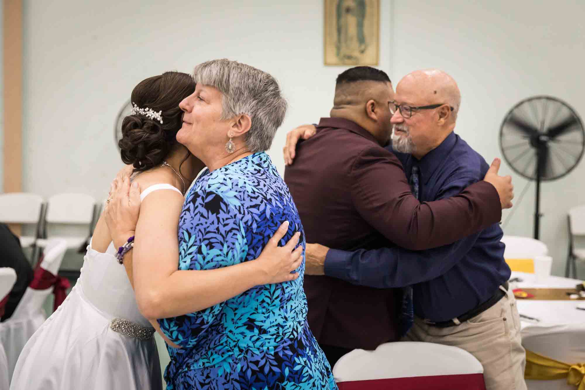 Bride and groom each hugging older couple during a St. Henry Catholic Church wedding reception