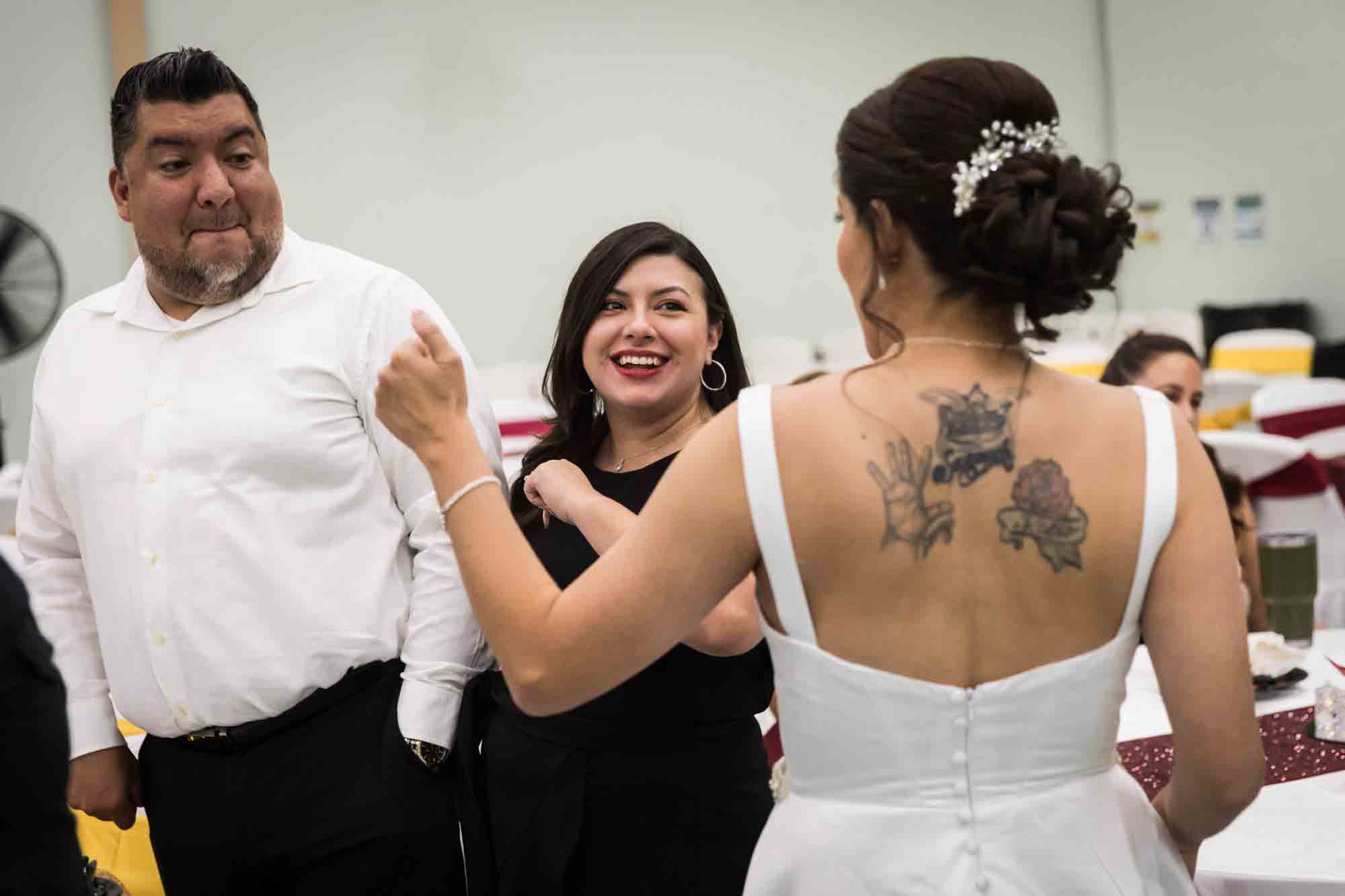 Bride talking to man and woman wearing black dress during a St. Henry Catholic Church wedding reception