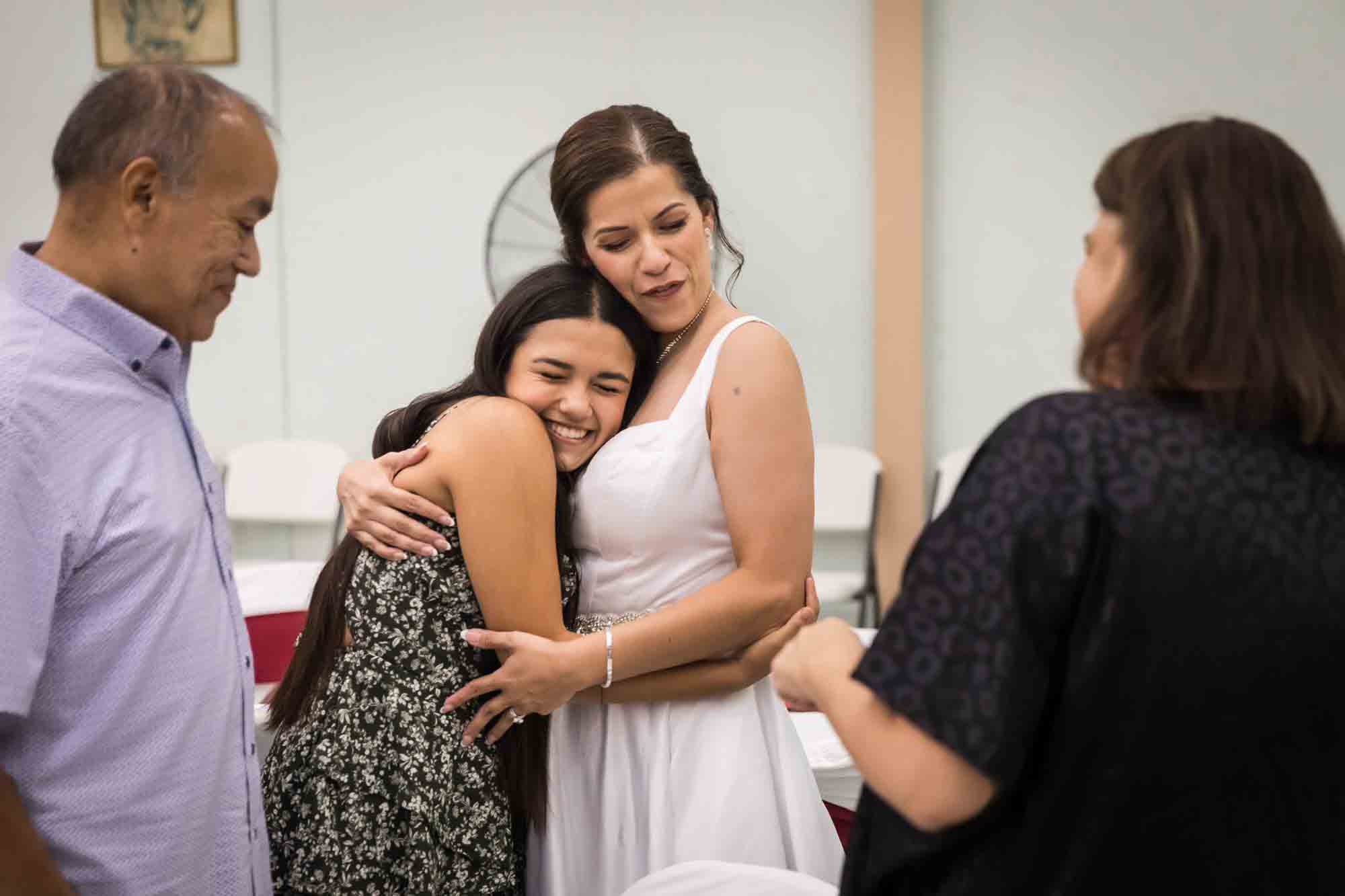 Bride hugging young girl in front of couple during a St. Henry Catholic Church wedding reception