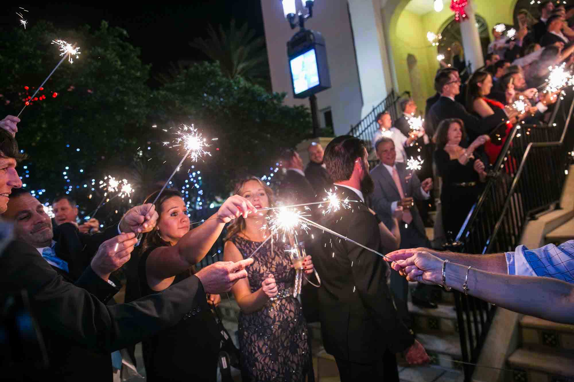 Wedding guests lighting sparklers outside for an article on how to have fireworks at an event in San Antonio