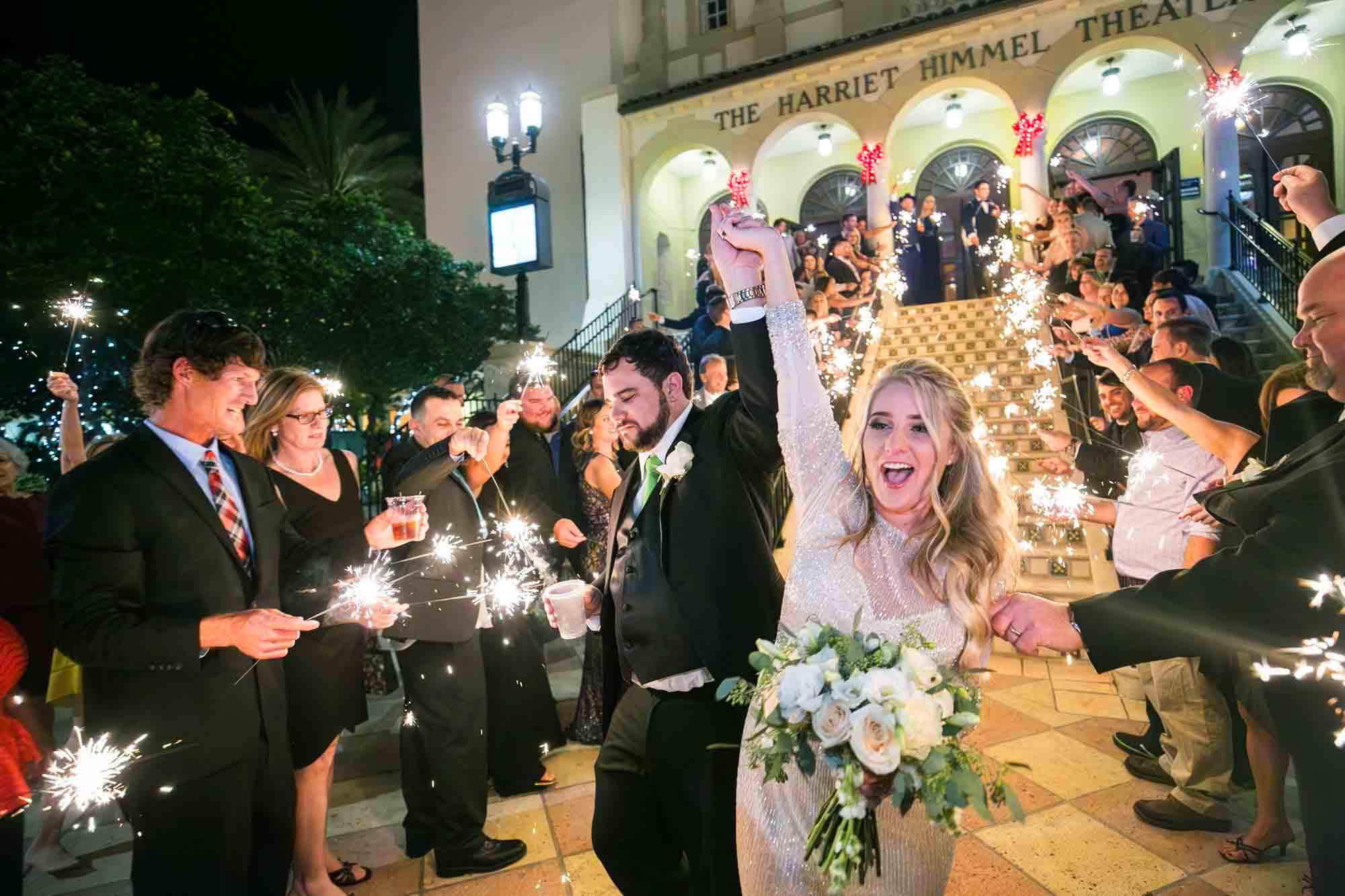 Wedding guests with sparklers cheering a bride and groom leaving a venue for an article on how to have fireworks at an event in San Antonio