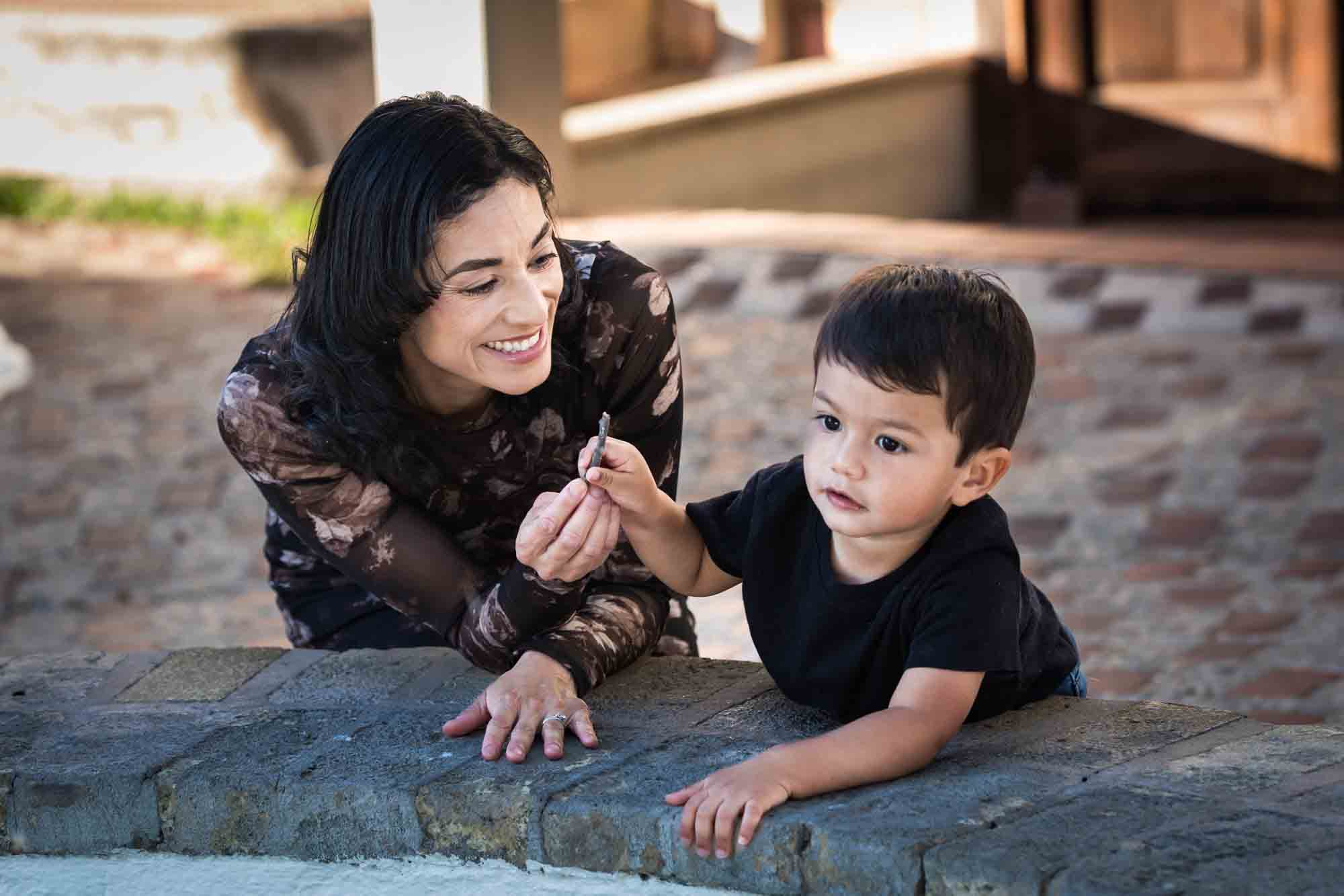 Mother playing with little boy with cobblestone patio in background at La Villita