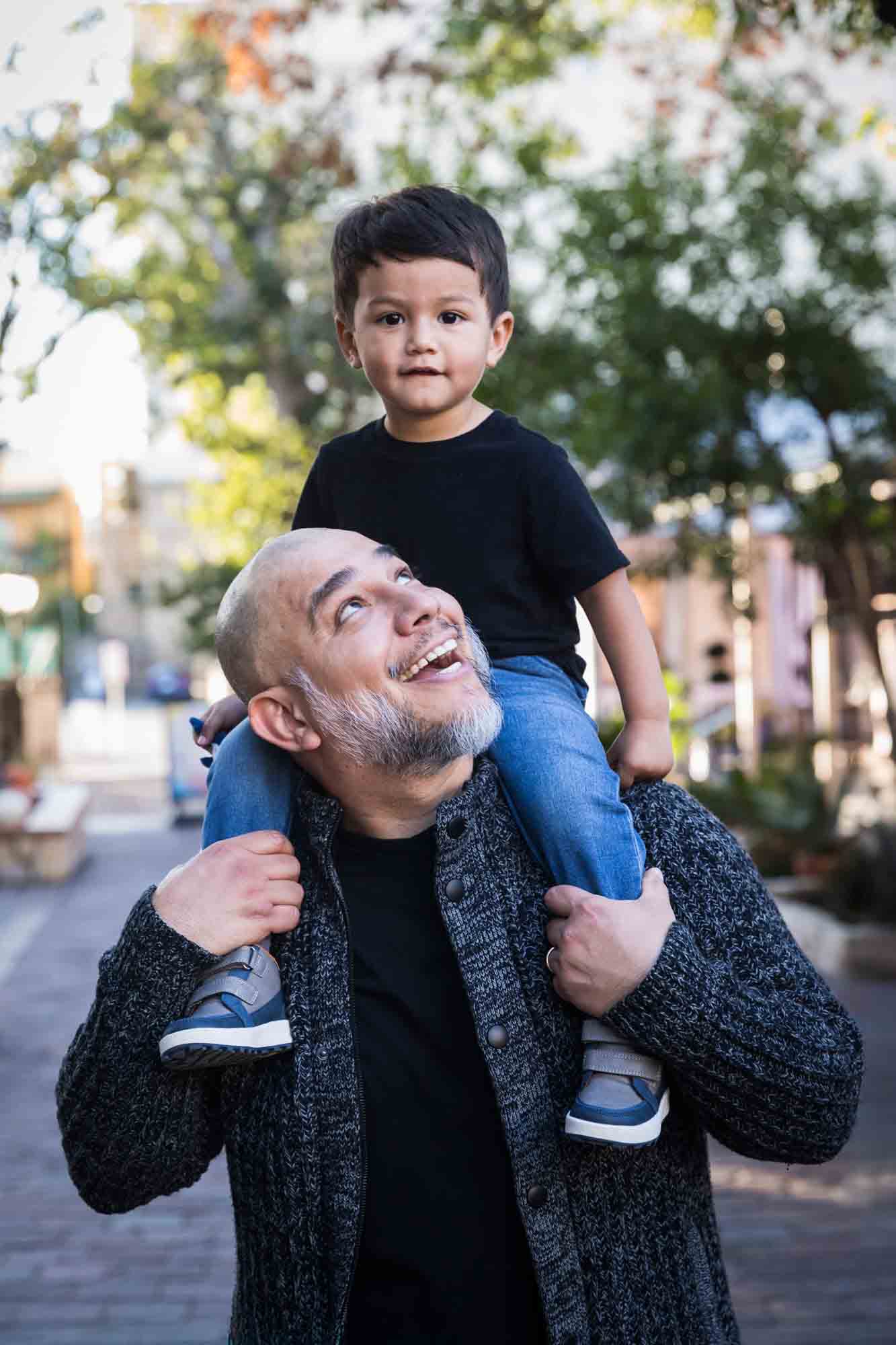 Father looking up at little boy sitting on his shoulders at La Villita