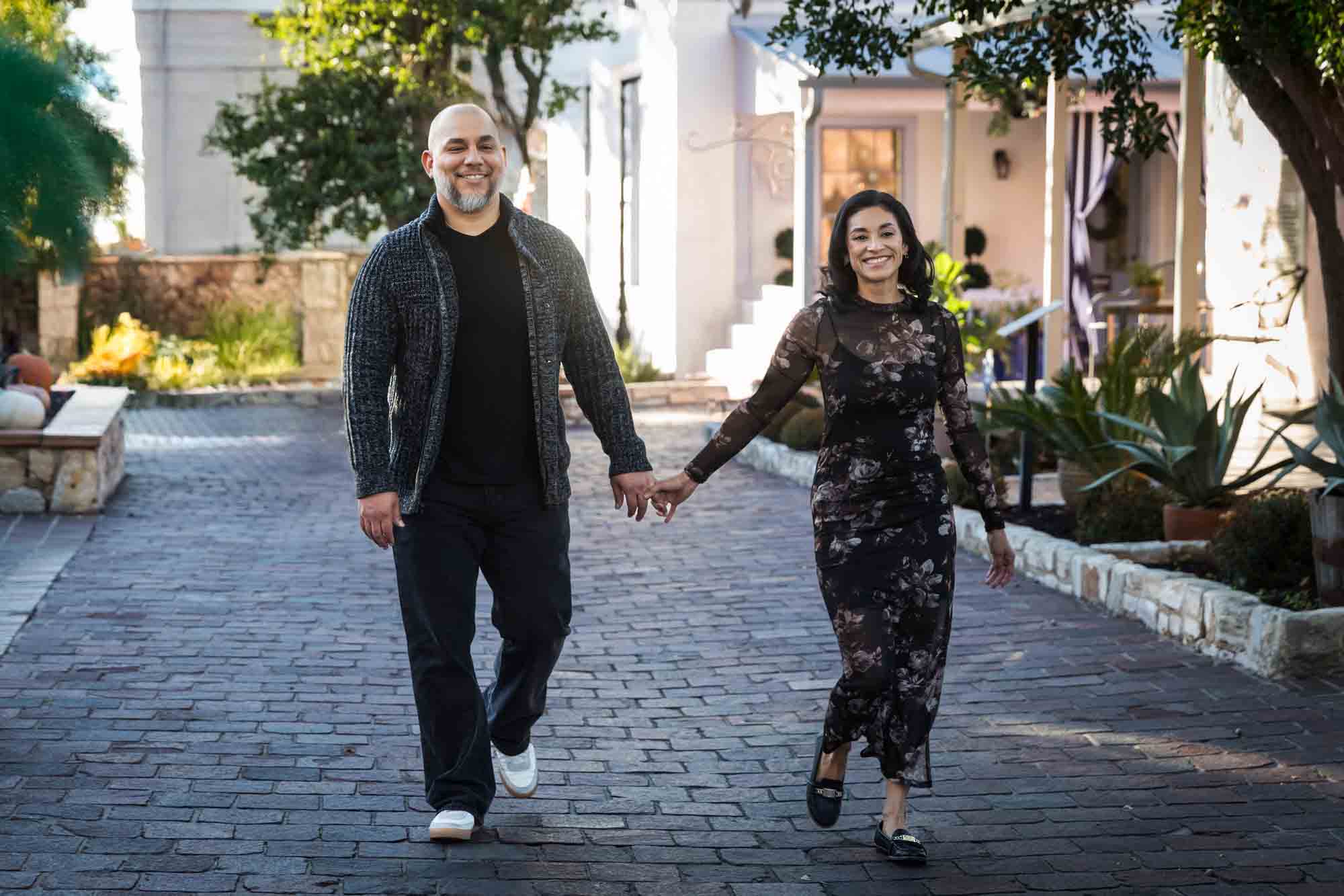 Parents holding hands and walking along cobblestone street during a La Villita family portrait session