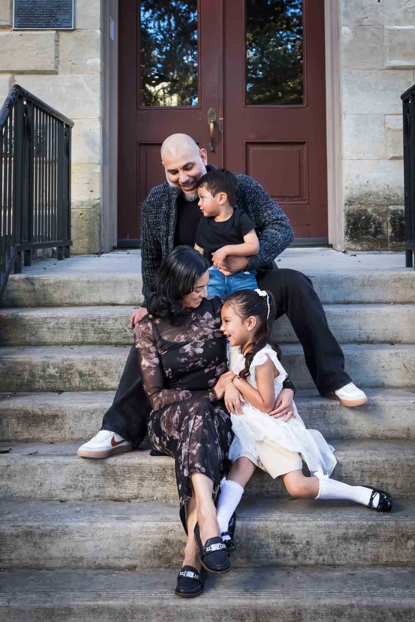 Parents and two young children sitting on steps of Little Church during a La Villita family portrait session