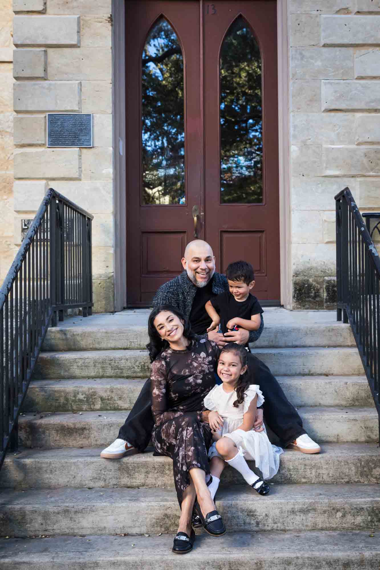 Parents and two young children sitting on steps of Little Church during a La Villita family portrait session