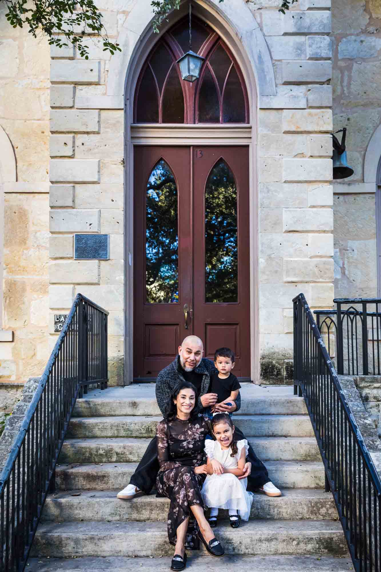 Parents and two young children sitting on steps of Little Church during a La Villita family portrait session