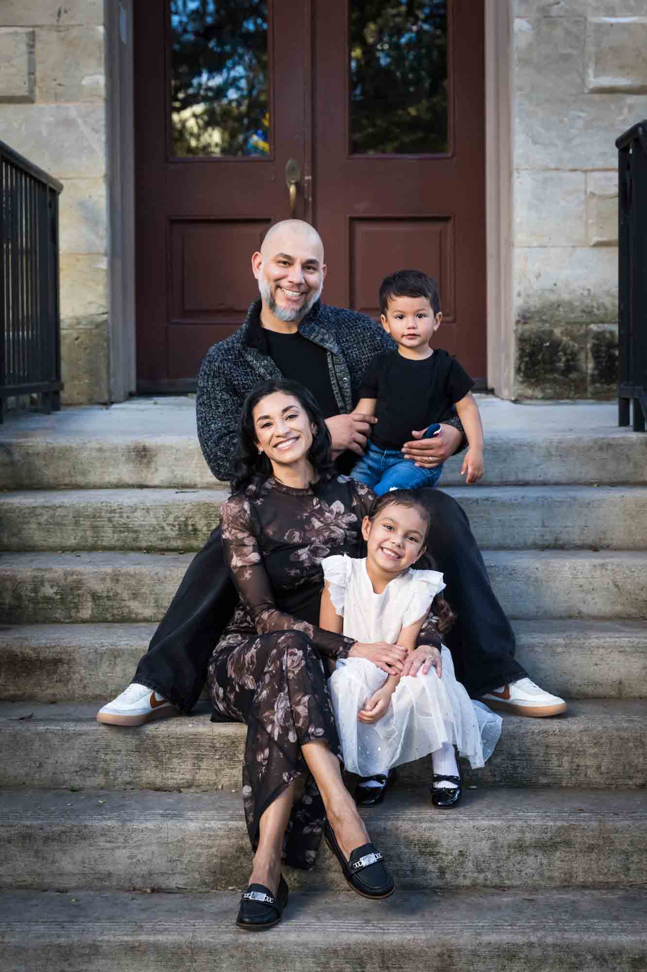 Parents and two young children sitting on steps of Little Church during a La Villita family portrait session