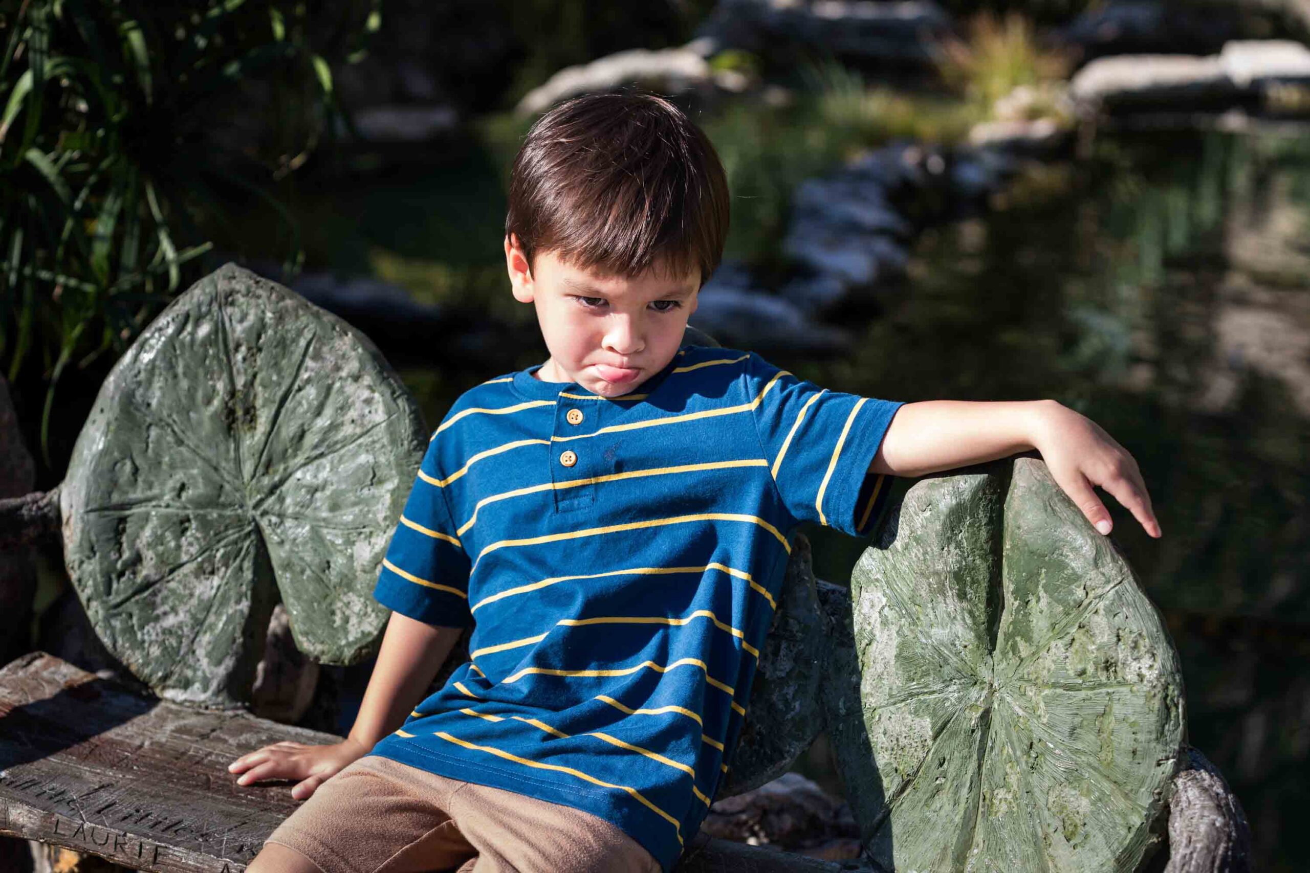 Little boy with brown hair seated wearing blue striped shirt for an article on photo tips for families with young children