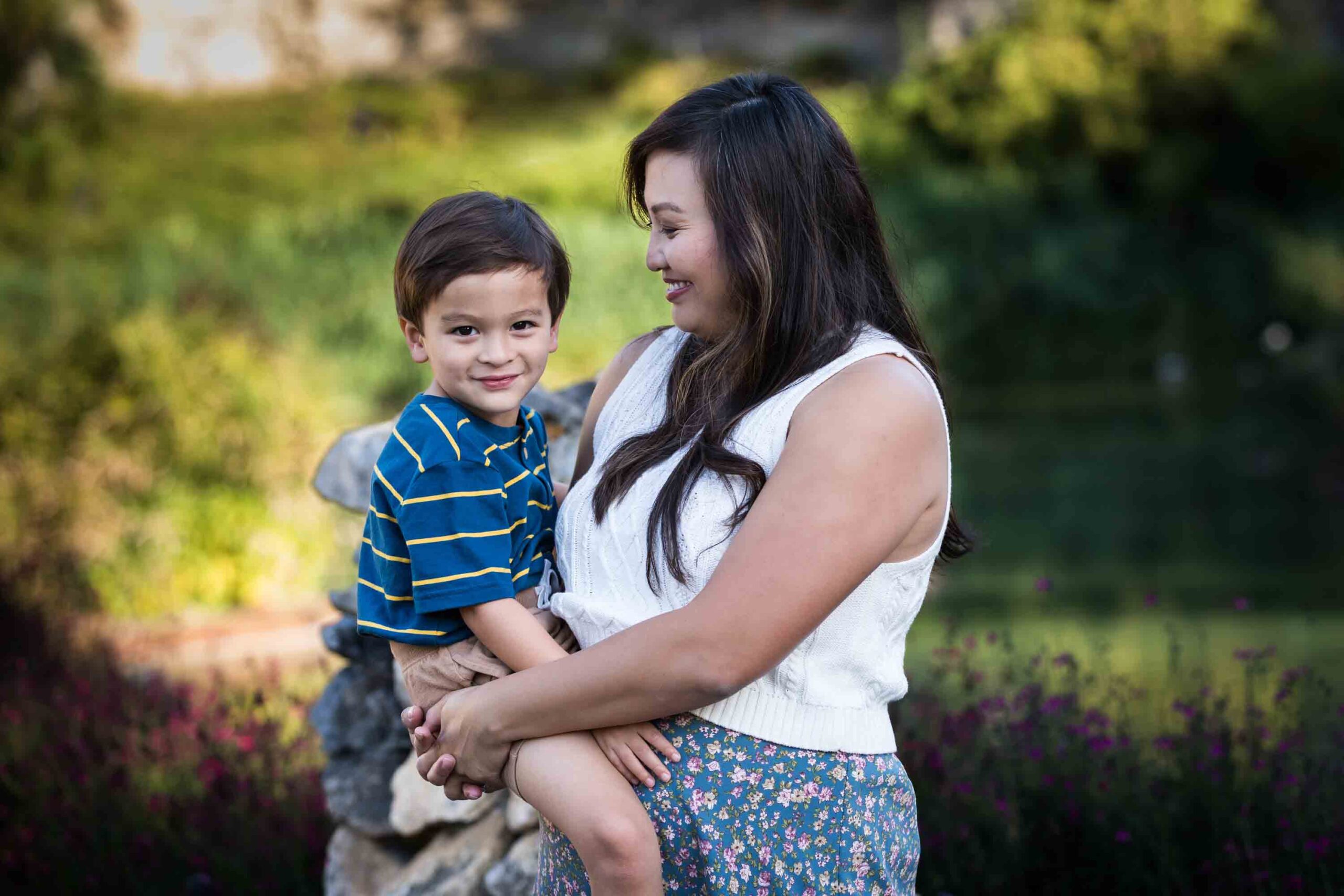 Mother holding little boy with brown hair wearing striped shirt for an article on photo tips for families with young children