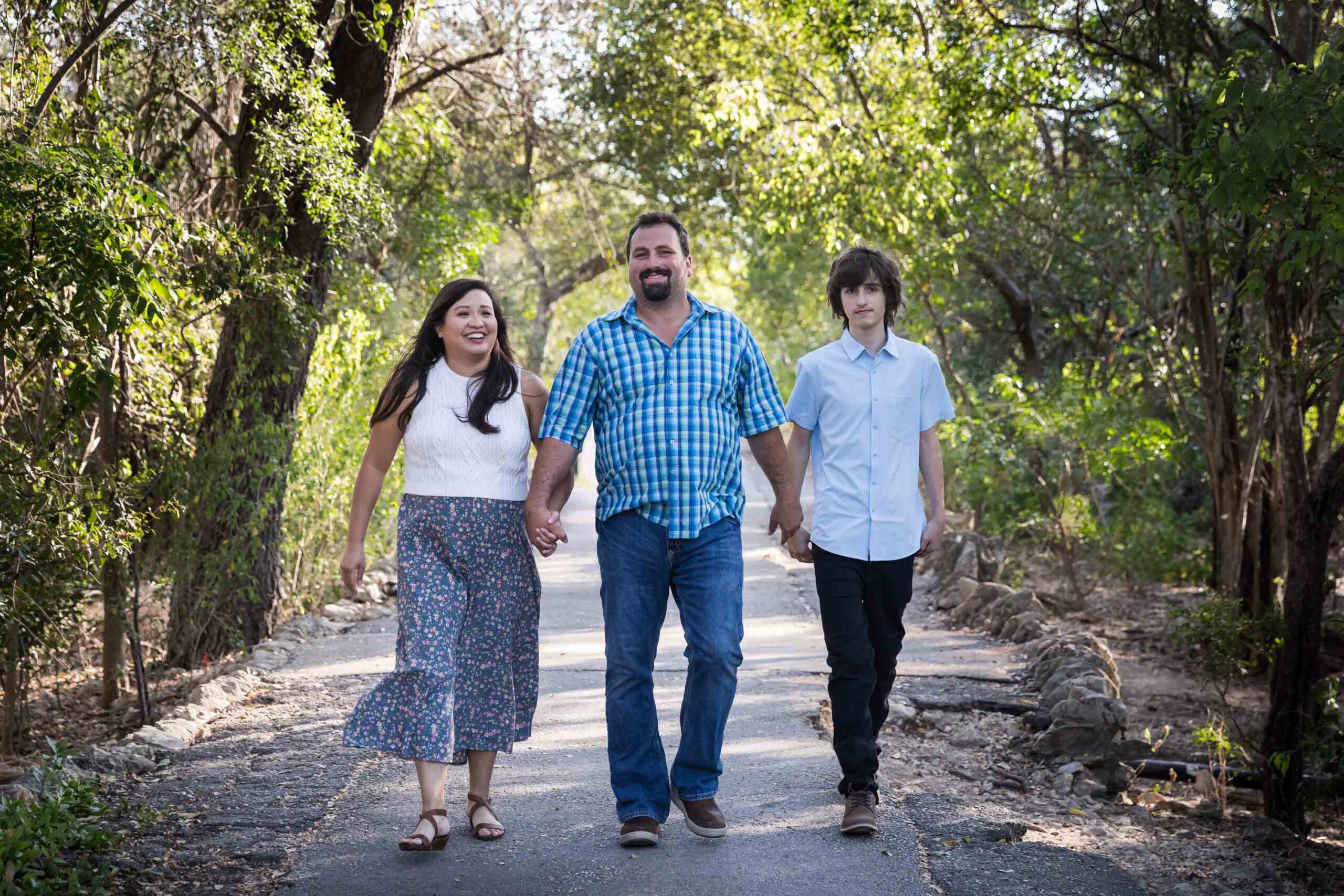 Parents walking with teenager boy in pathway in forested park for an article on photo tips for families with young children