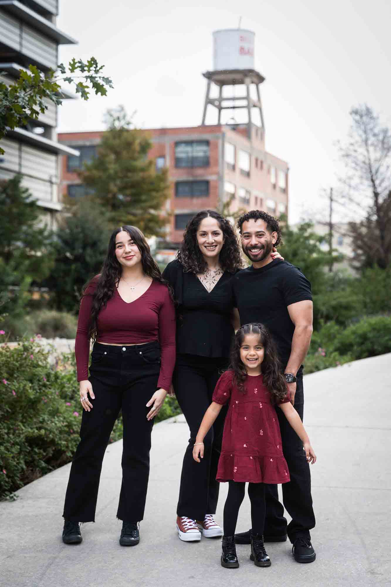 Family of parents, teen girl, and little girl hugging on sidewalk during a San Pedro Creek Park family portrait session