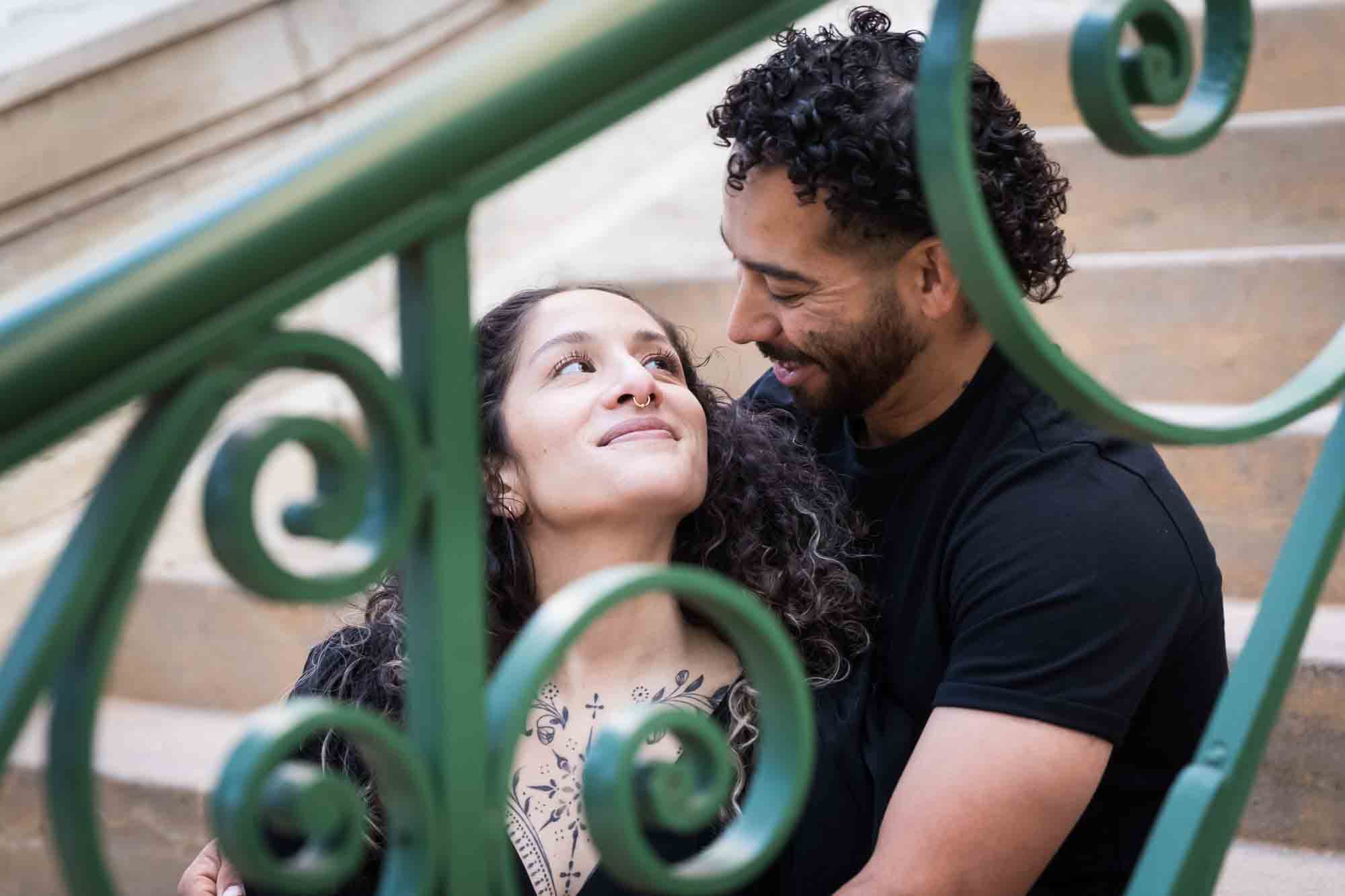 Couple wearing black t-shirts sitting closely on stairs behind green railing