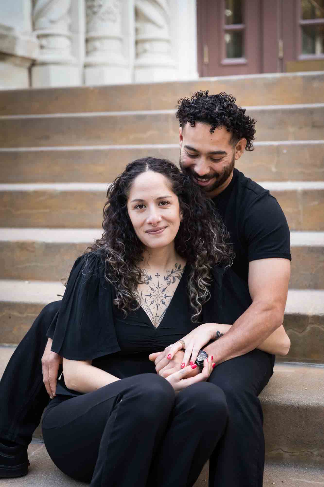 Couple wearing black t-shirts sitting closely on stairs