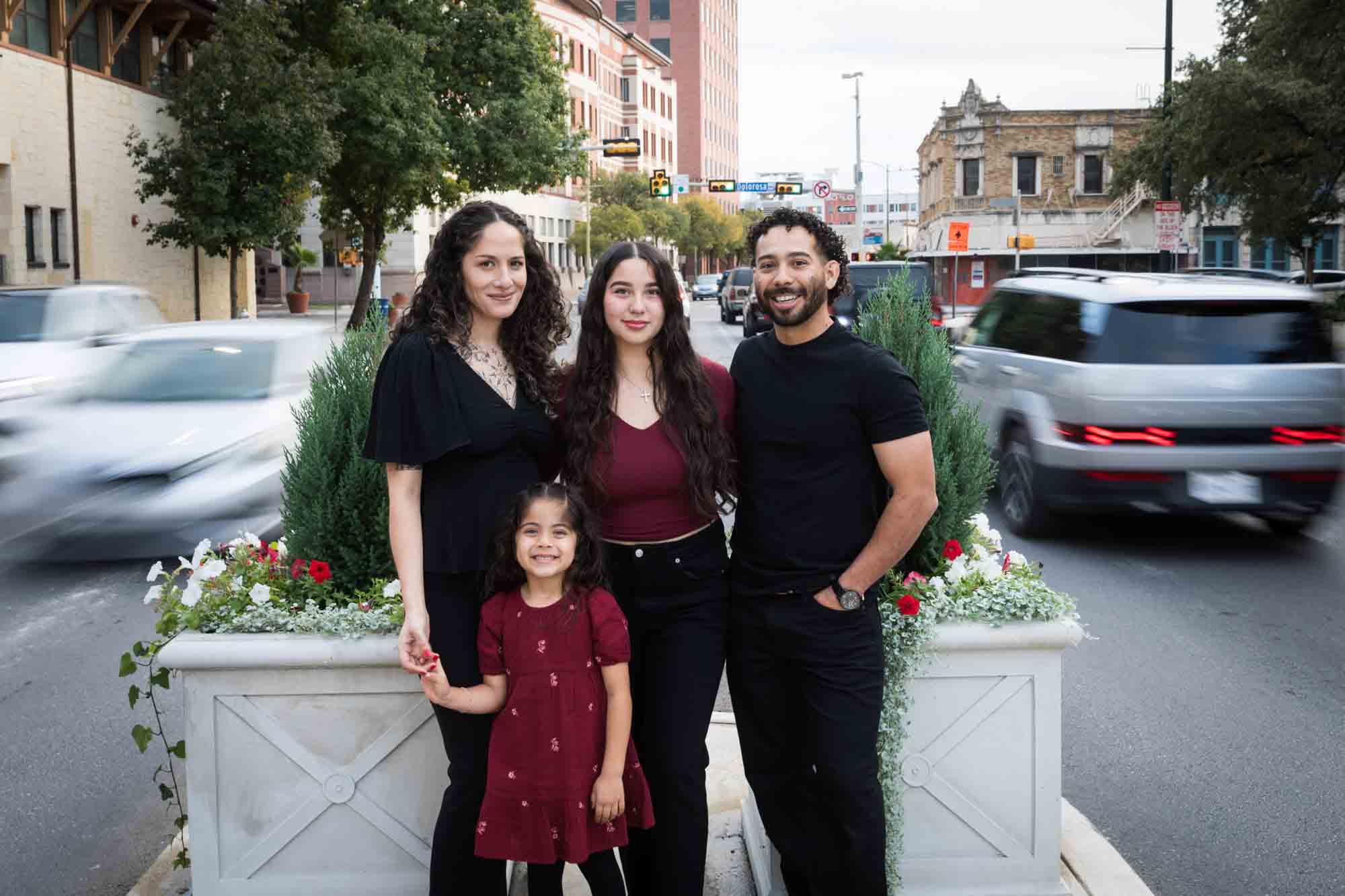 Parents and two girls standing in middle of road with blur of cars going past