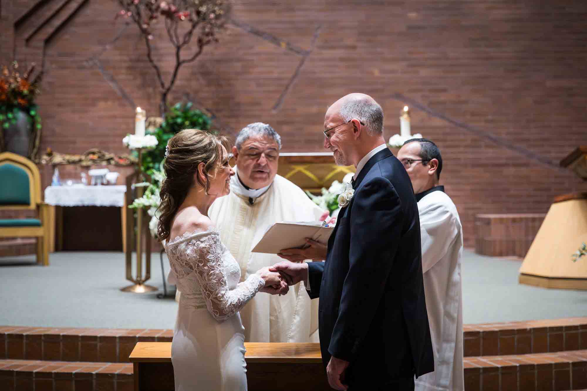 Bride and groom saying vows in front of priest at a St. Mark the Evangelist Catholic Church wedding