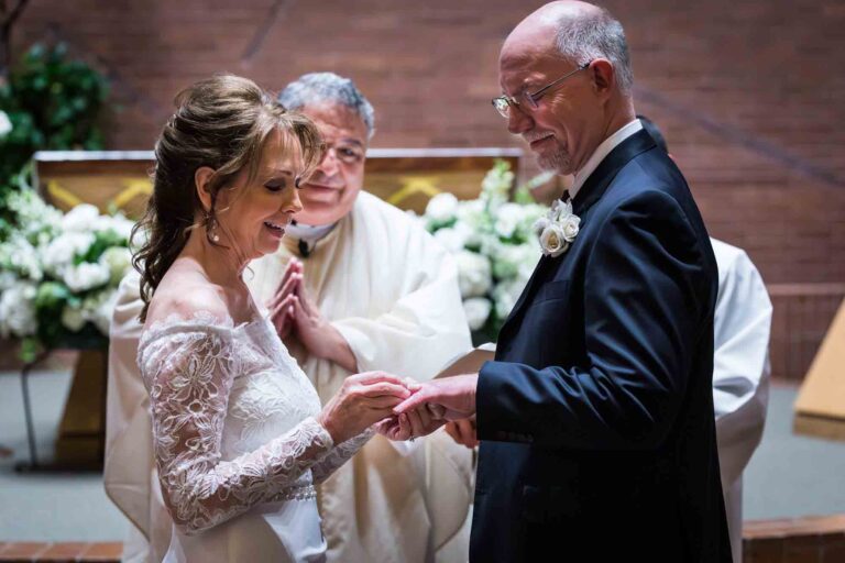 Bride putting ring on groom's finger at a St. Mark the Evangelist Catholic Church wedding