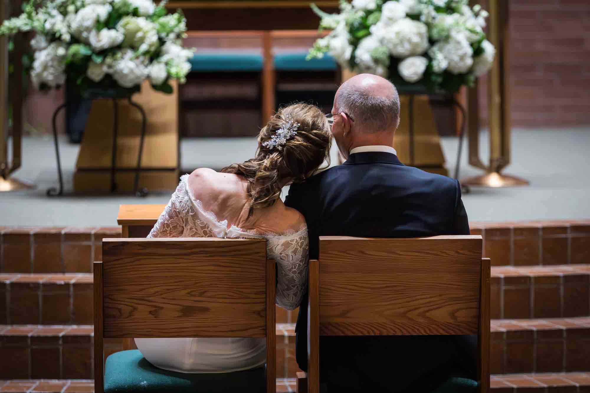 Bride resting head on groom's shoulder from behind at a St. Mark the Evangelist Catholic Church wedding