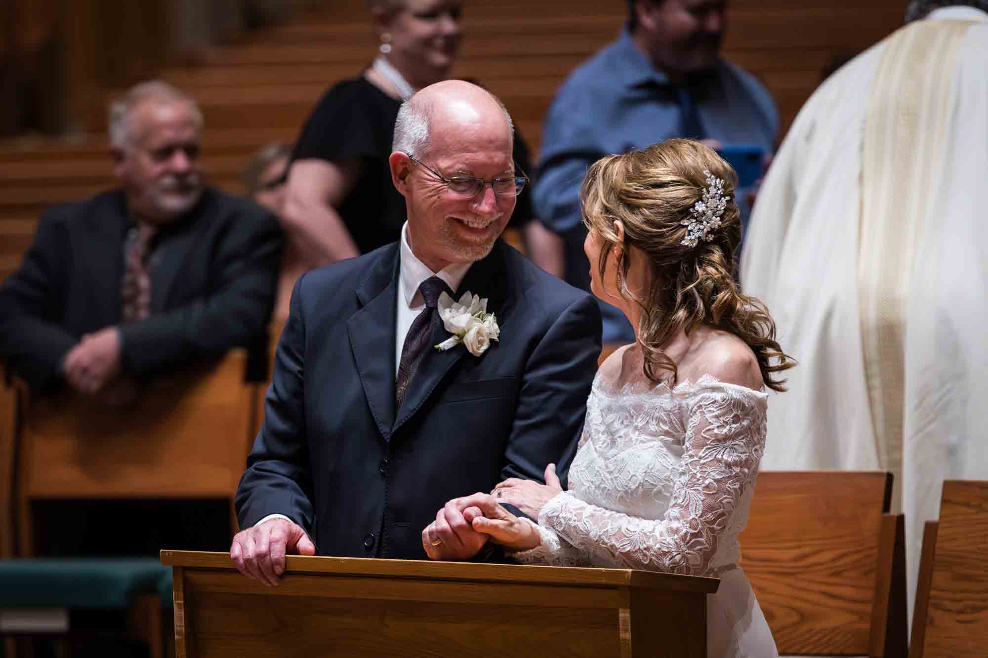 Bride and groom holding hands and looking at each other at a St. Mark the Evangelist Catholic Church wedding