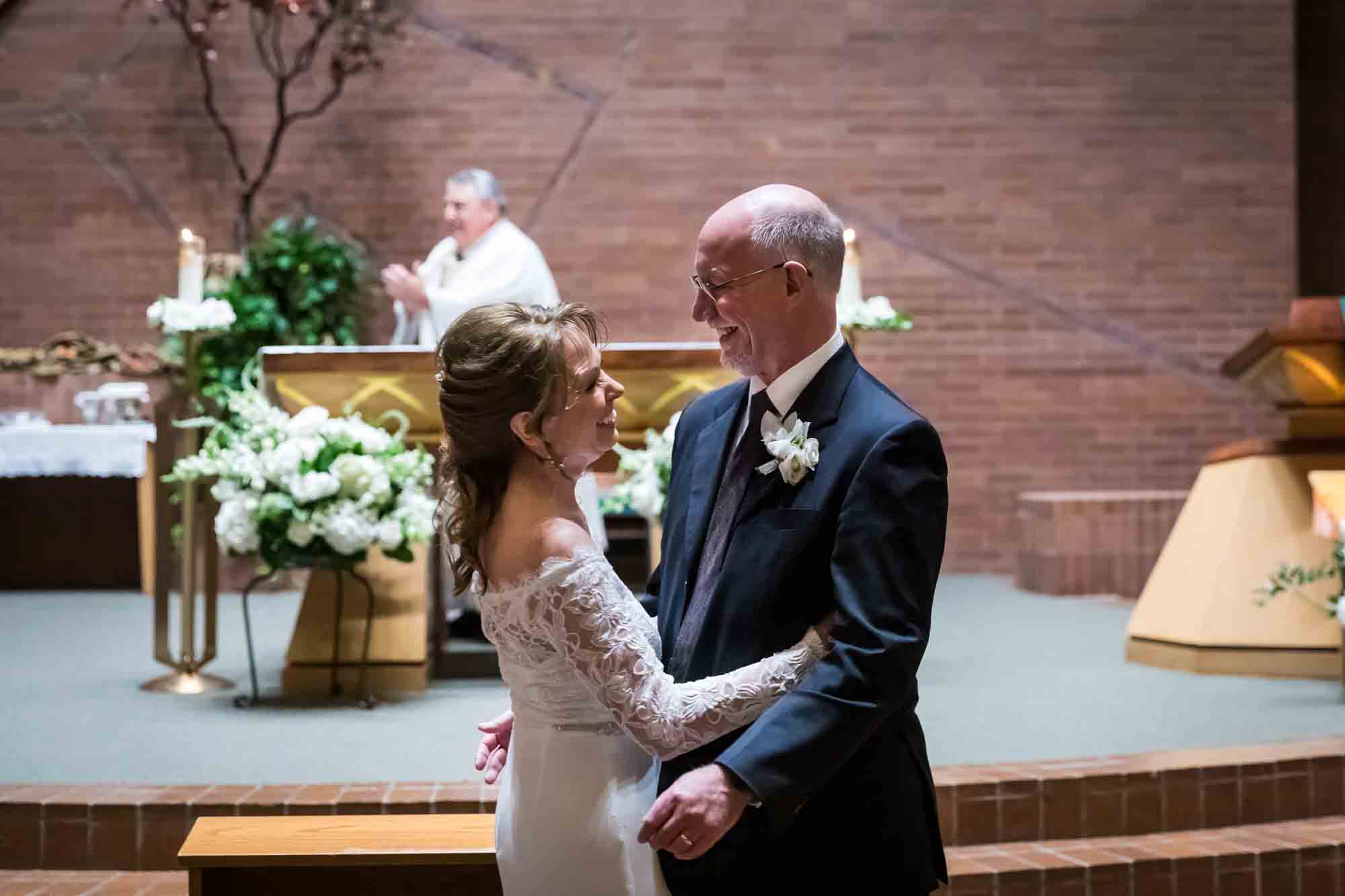 Bride and groom hugging in front of altar at a St. Mark the Evangelist Catholic Church wedding