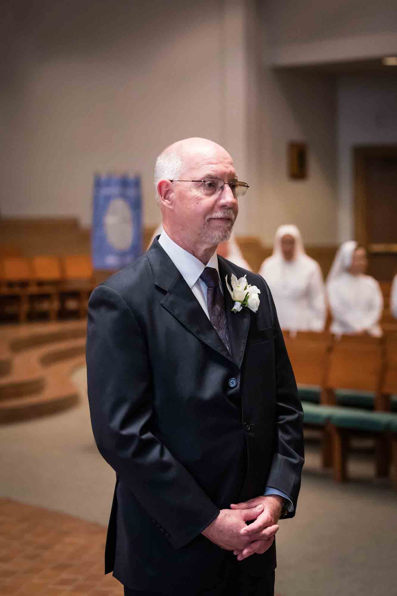 Older man wearing suit waiting at end of aisle for bride at a St. Mark the Evangelist Catholic Church wedding