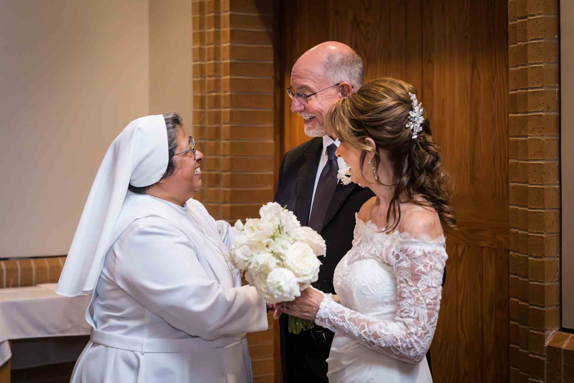 Bride and groom holding hands with a nun at a St. Mark the Evangelist Catholic Church wedding