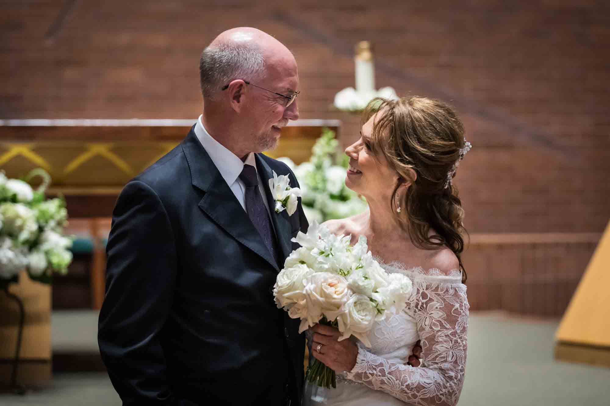 Bride and groom looking at each other in front of altar at a St. Mark the Evangelist Catholic Church wedding