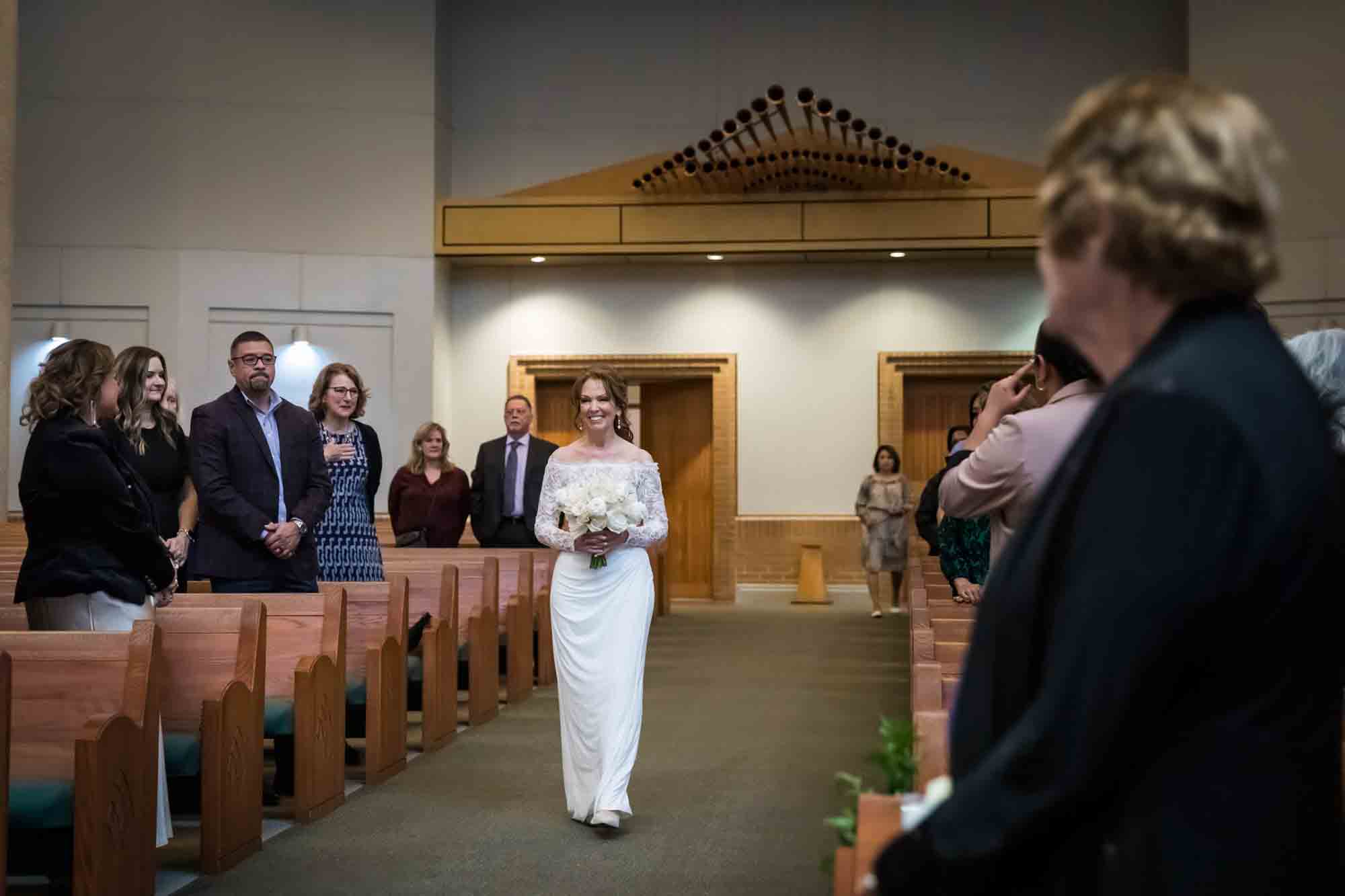 Bride walking down the aisle surrounded by guests at a St. Mark the Evangelist Catholic Church wedding