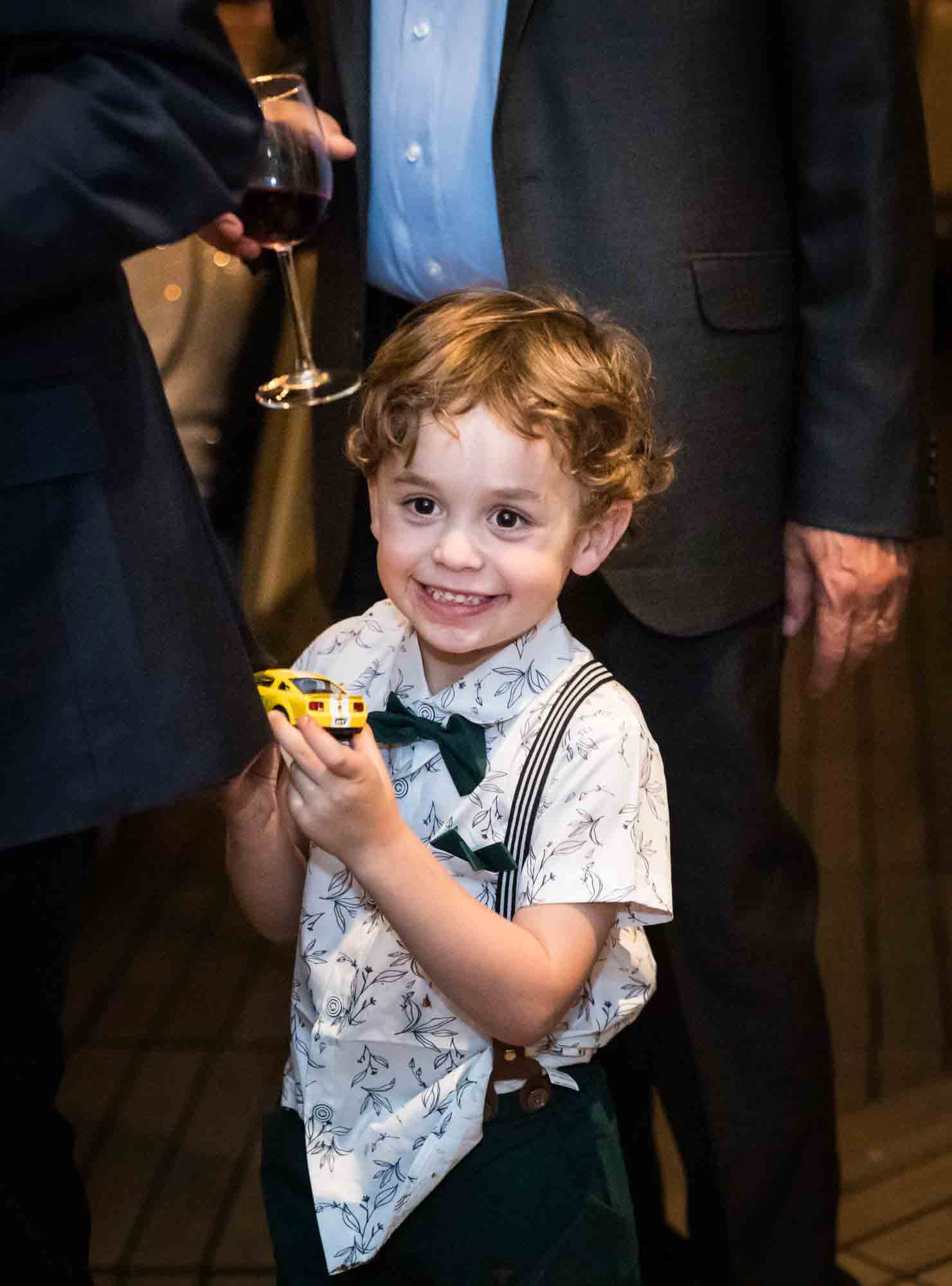 Little boy holding yellow toy car during wedding reception