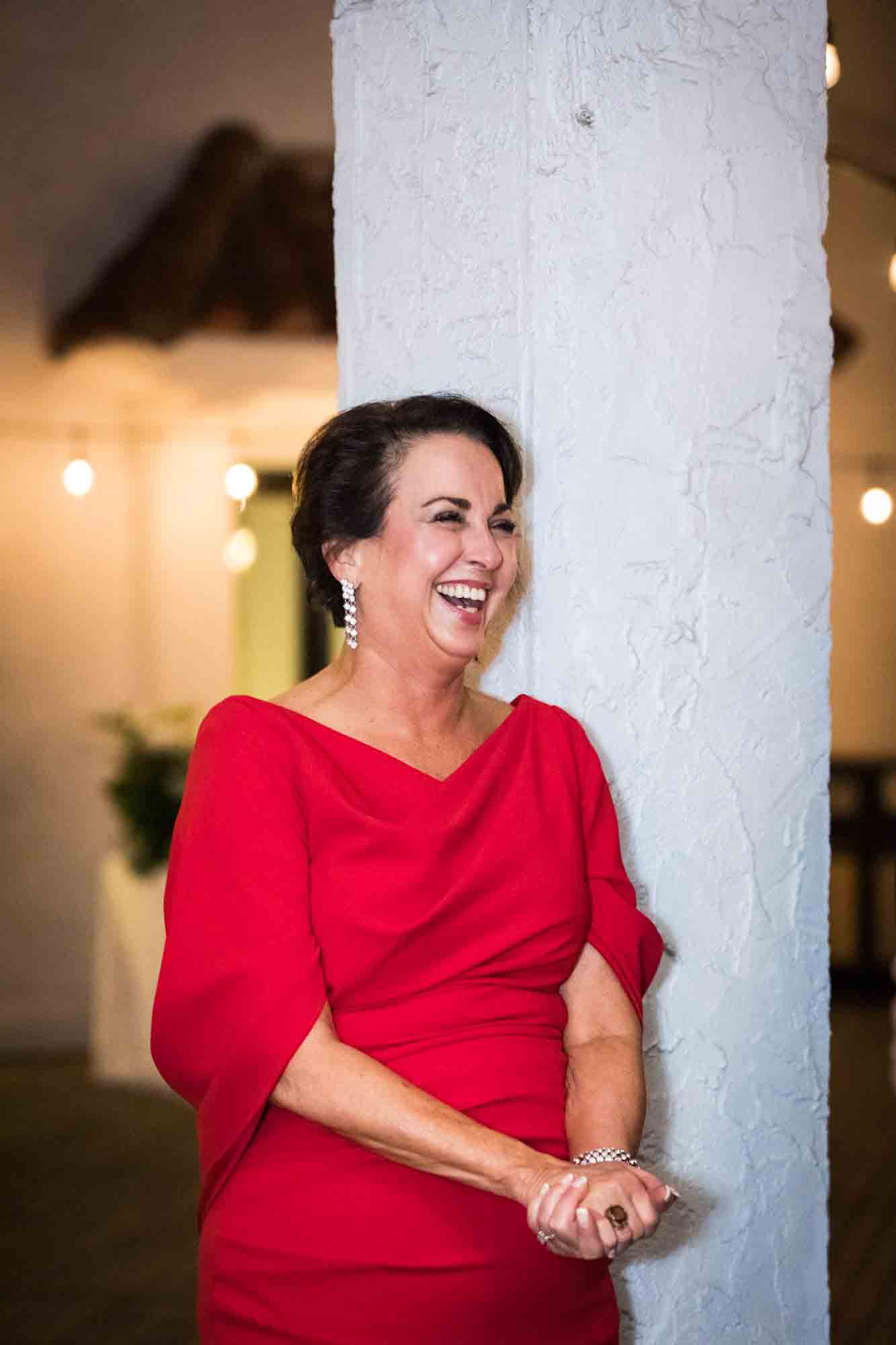 Woman in red dress standing against white column during St. Anthony Hotel wedding reception