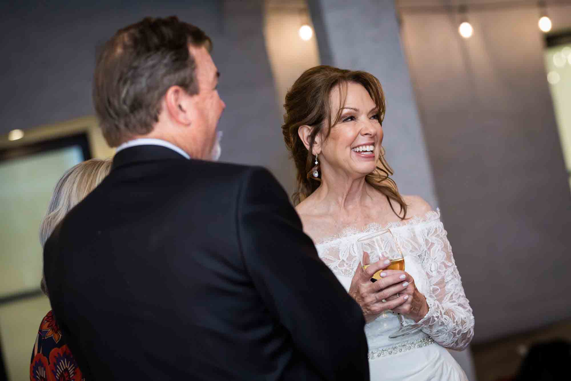 Bride laughing with man wearing black blazer during St. Anthony Hotel wedding reception