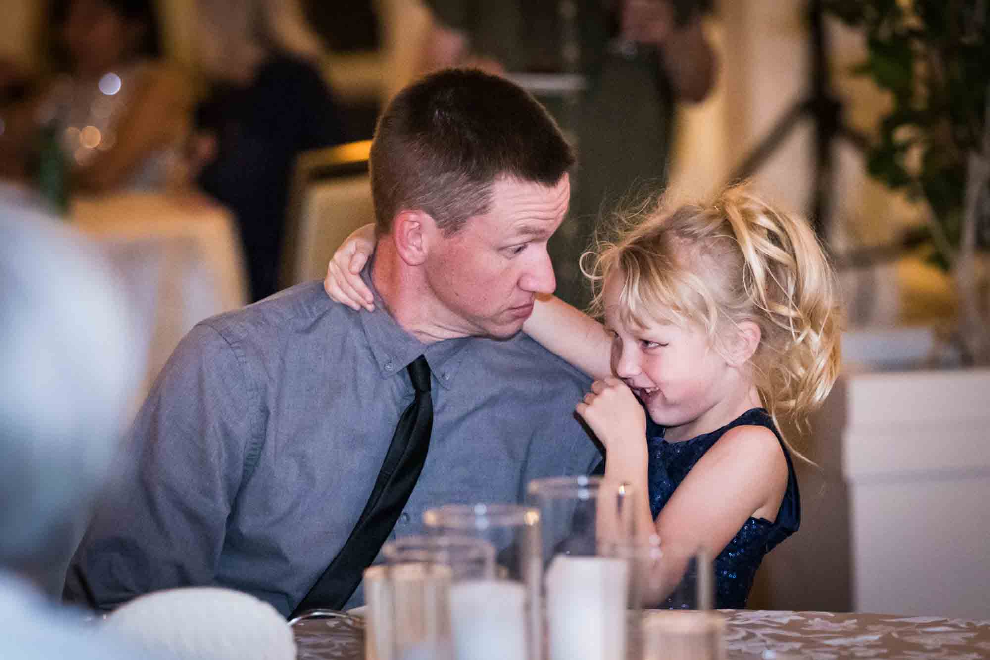 Father joking with little blonde girl at table during St. Anthony Hotel wedding reception