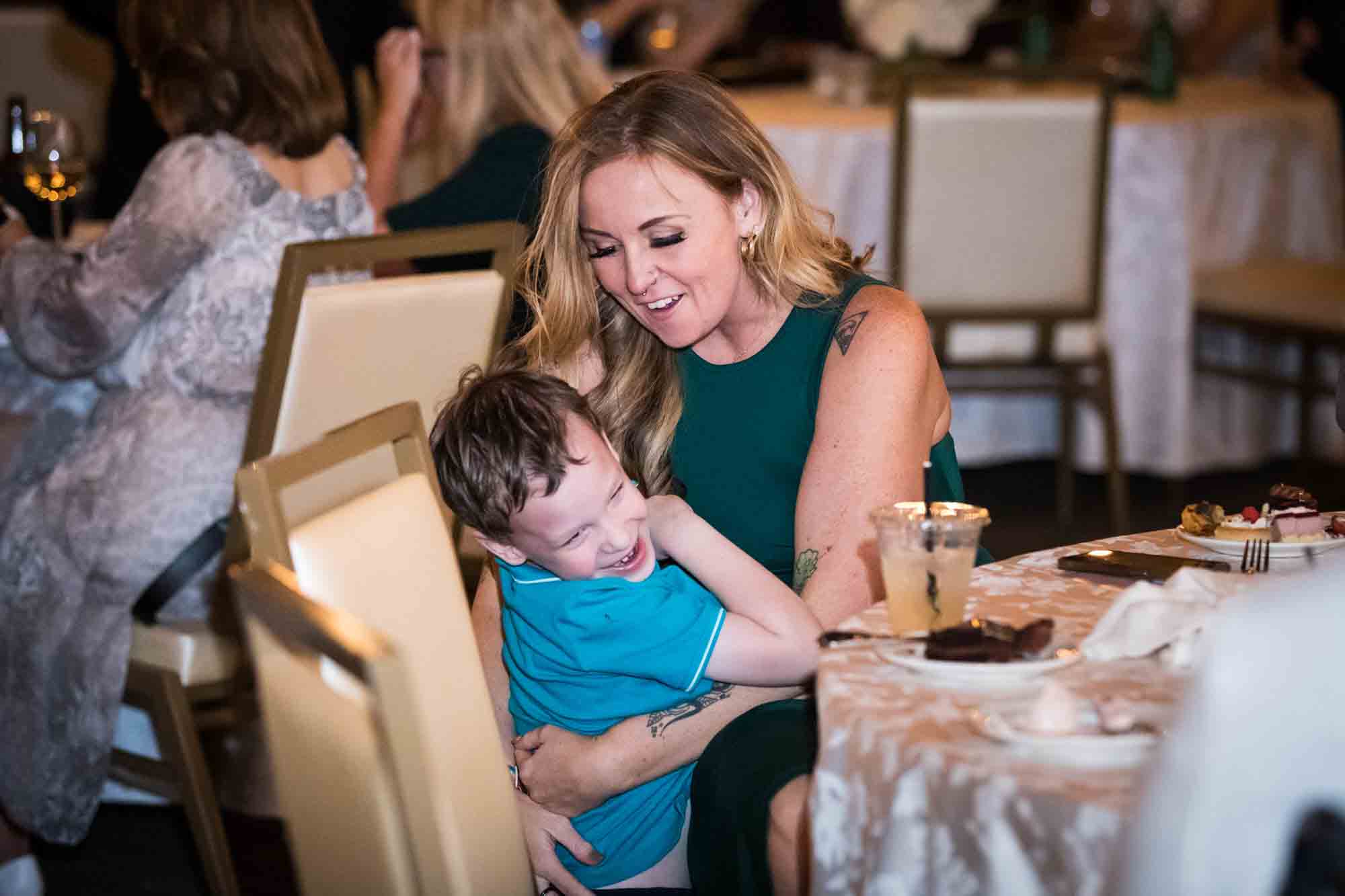 Mother playing with little boy wearing blue shirt at table during St. Anthony Hotel wedding reception